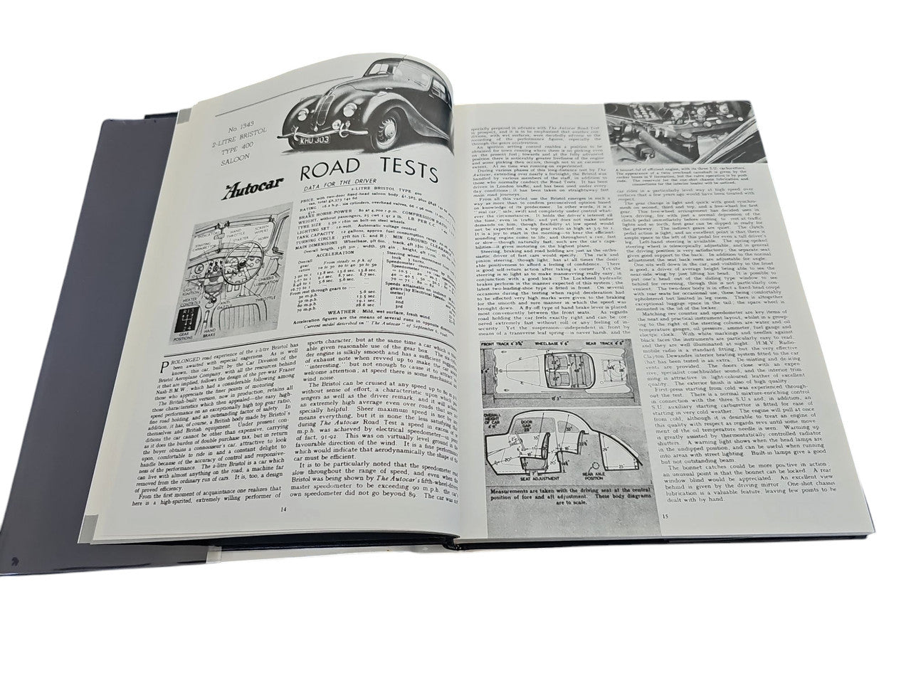 Hardcover automotive portfolio book open to article text and labeled road test charts