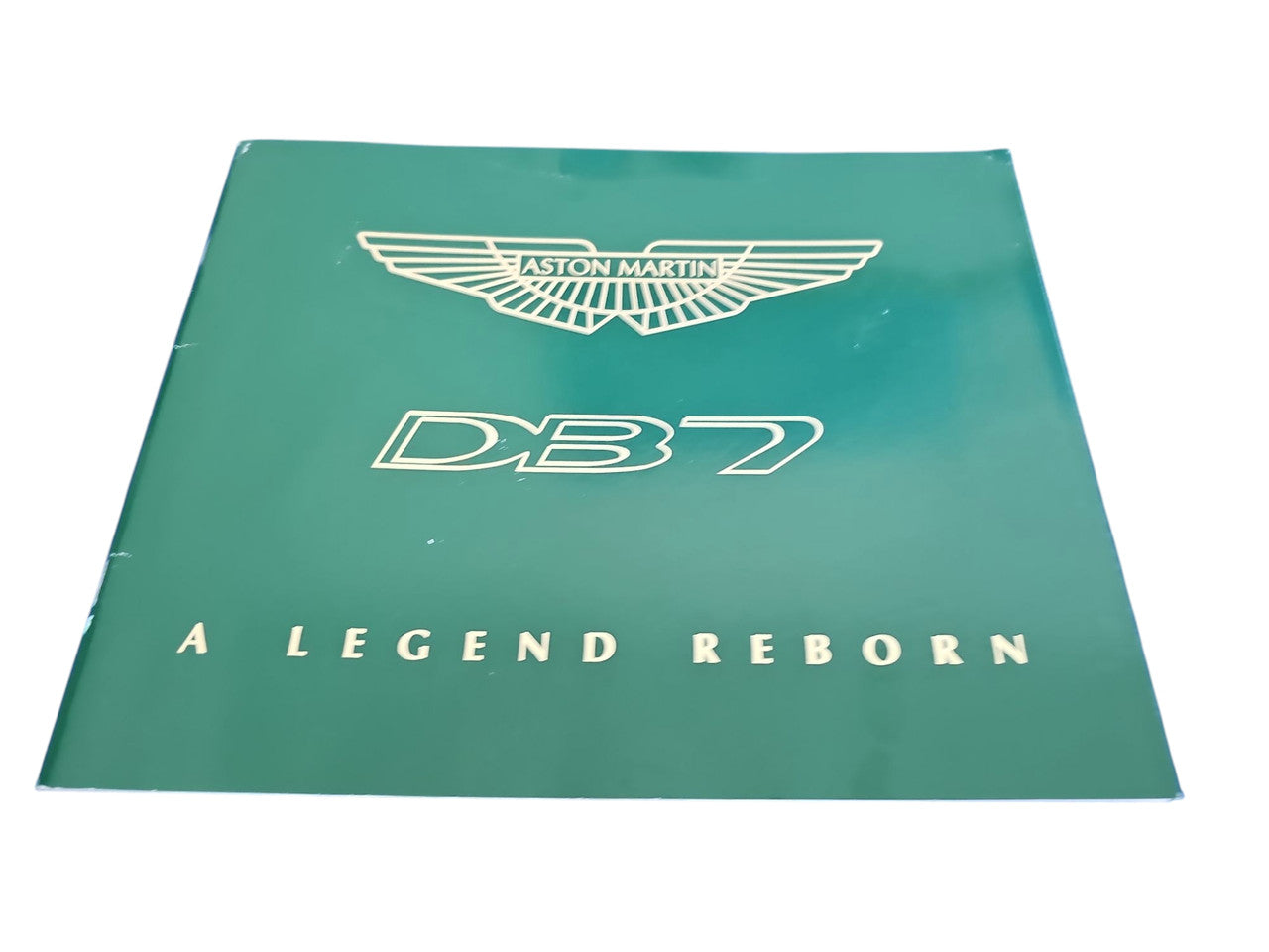 Aston Martin DB7 book with teal cover, wing logo, and “A Legend Reborn” title