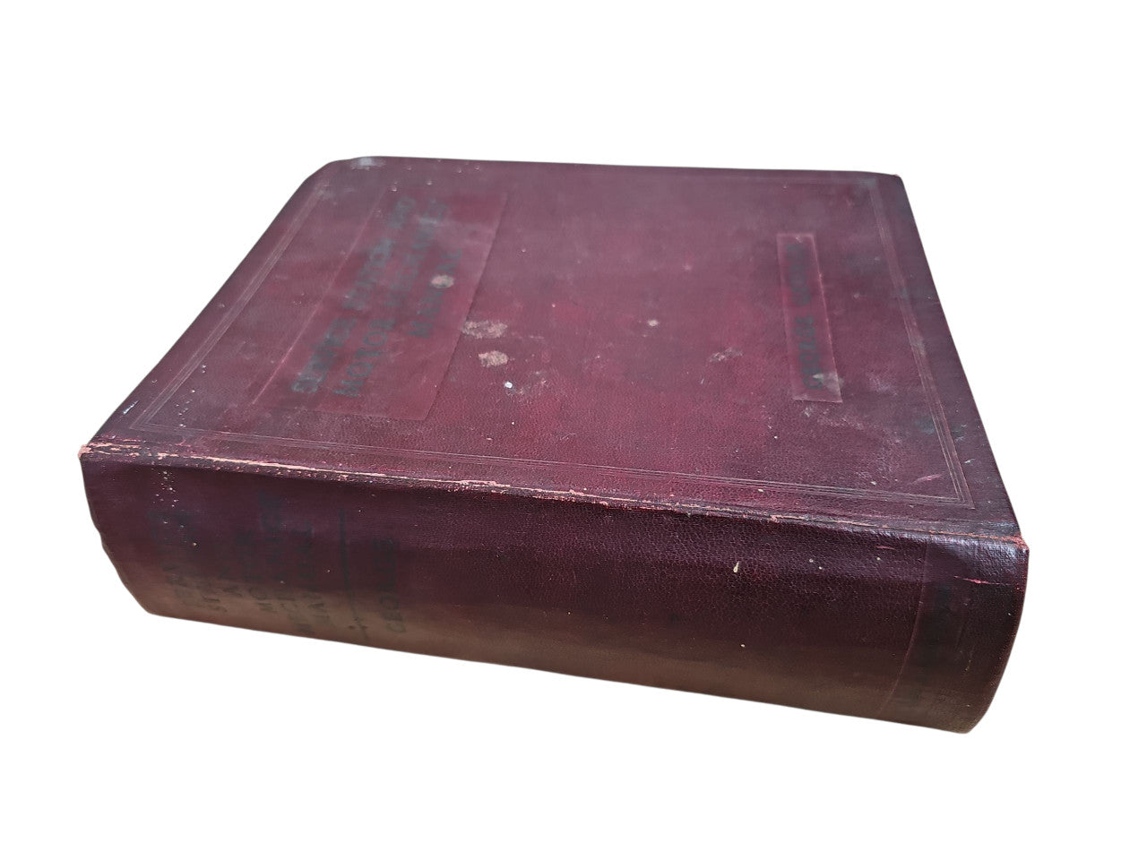 Burgundy vintage manual book with worn hard cover and visible spine edge