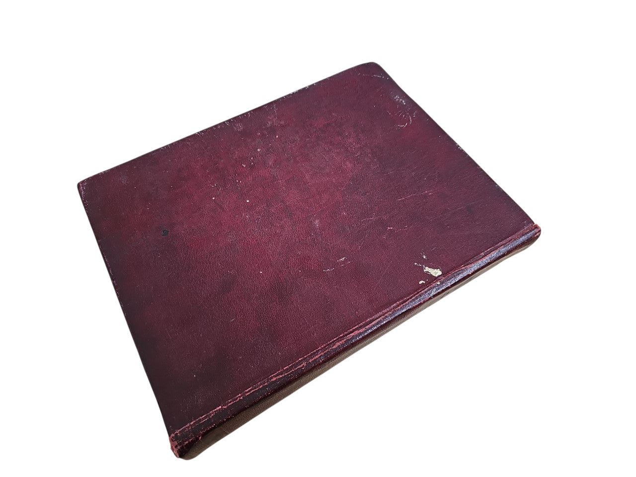 Burgundy hardcover manual book angled with scuffed cover surface
