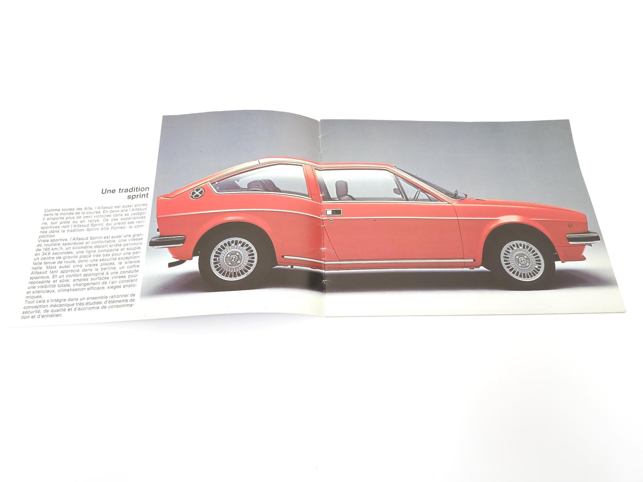 Open vintage brochure spread with side view of orange coupe and printed text
