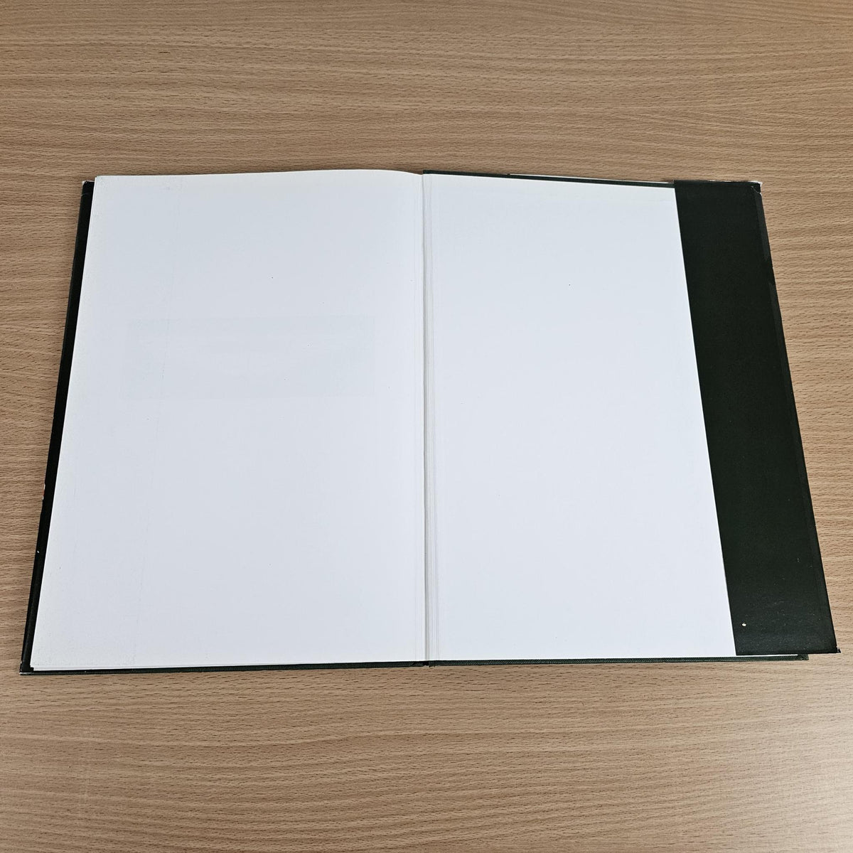 Open hardcover book with blank white pages and dark outer covers
