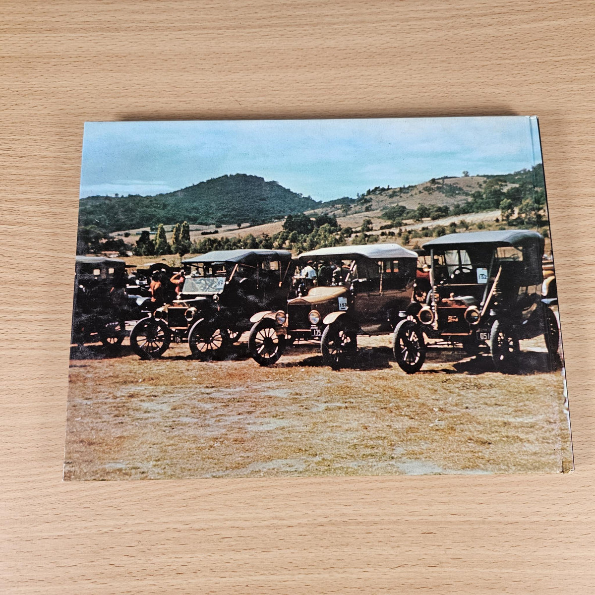 Hardcover automotive history book, back cover with photo of vintage cars outdoors.