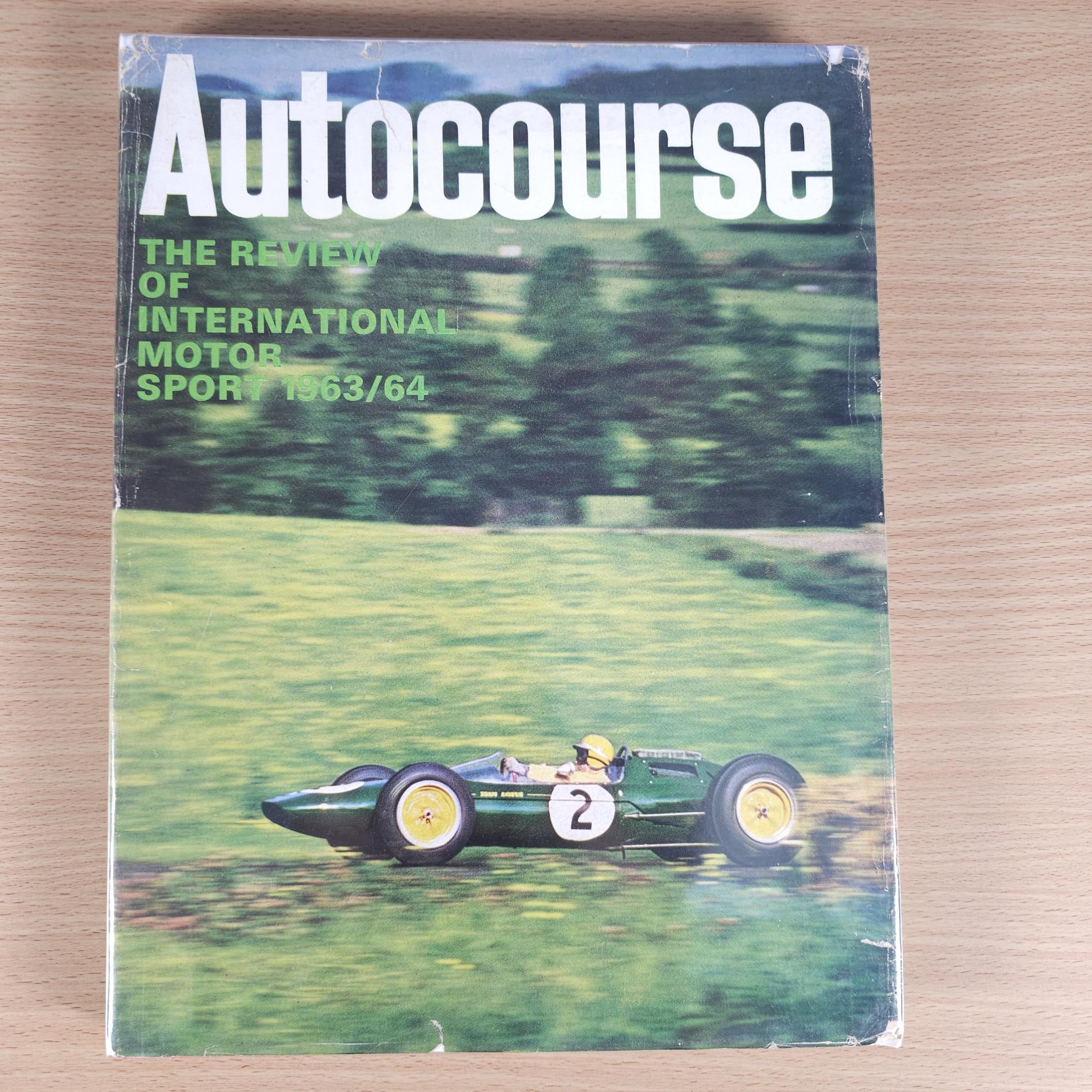 Vintage “Autocourse” book front cover with race car and green countryside scene.