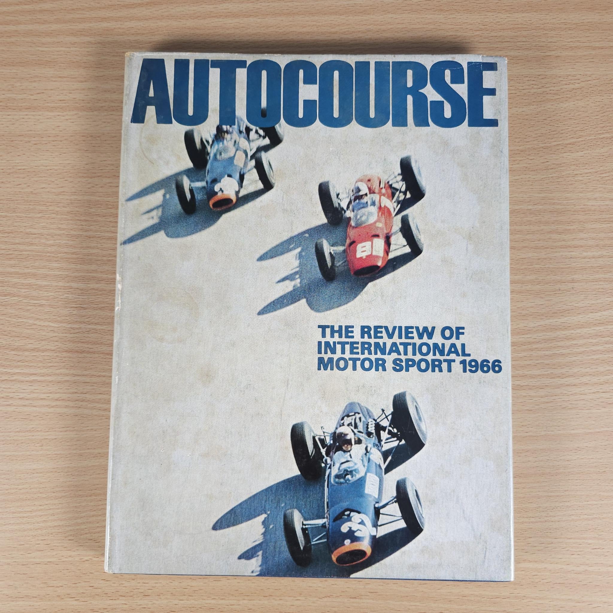 Vintage motorsport review book with Autocourse cover and racing car artwork on white