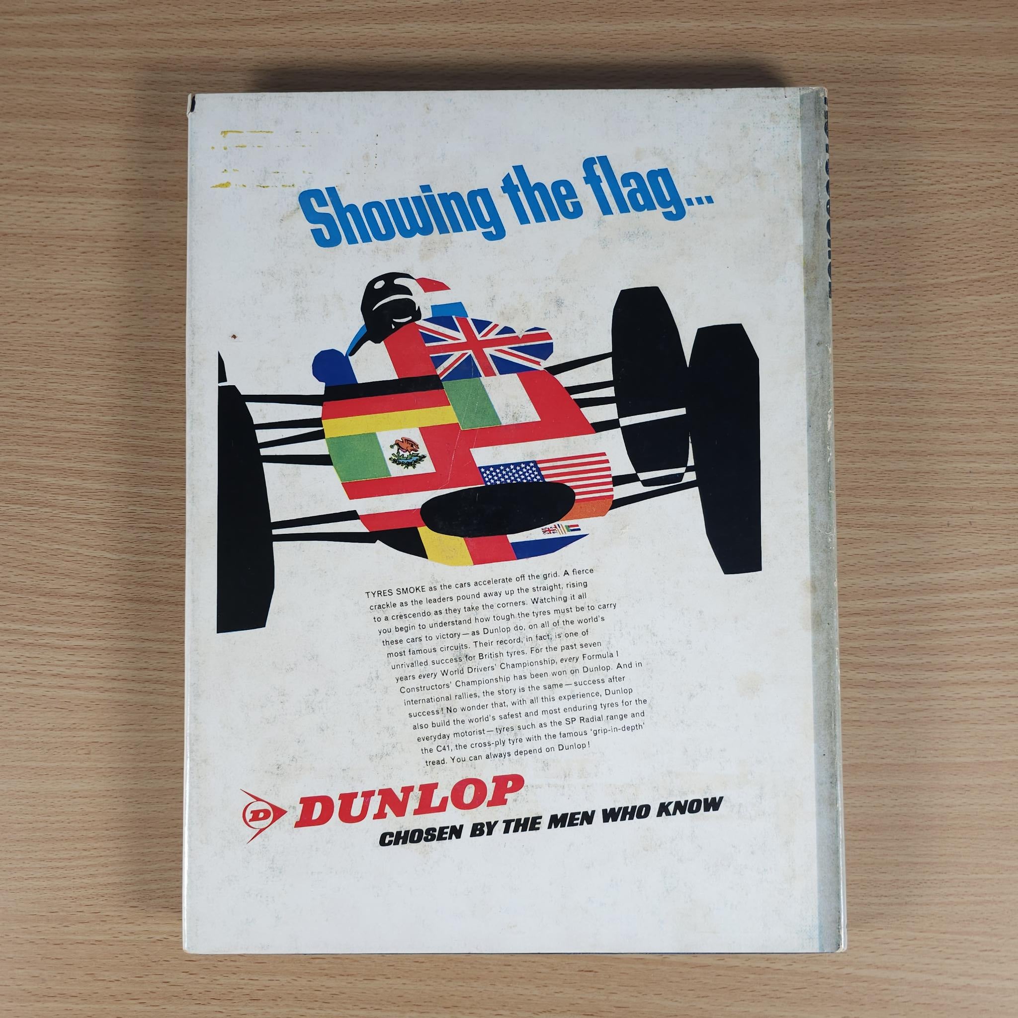 Vintage motorsport review book back cover with flags graphic and DUNLOP branding