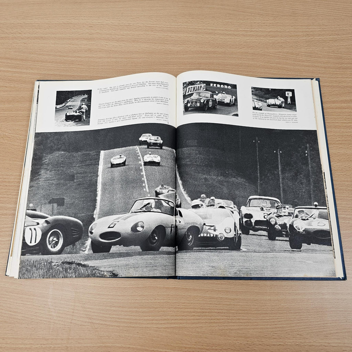 Open vintage automobile book with large black-and-white photo of cars lined on track