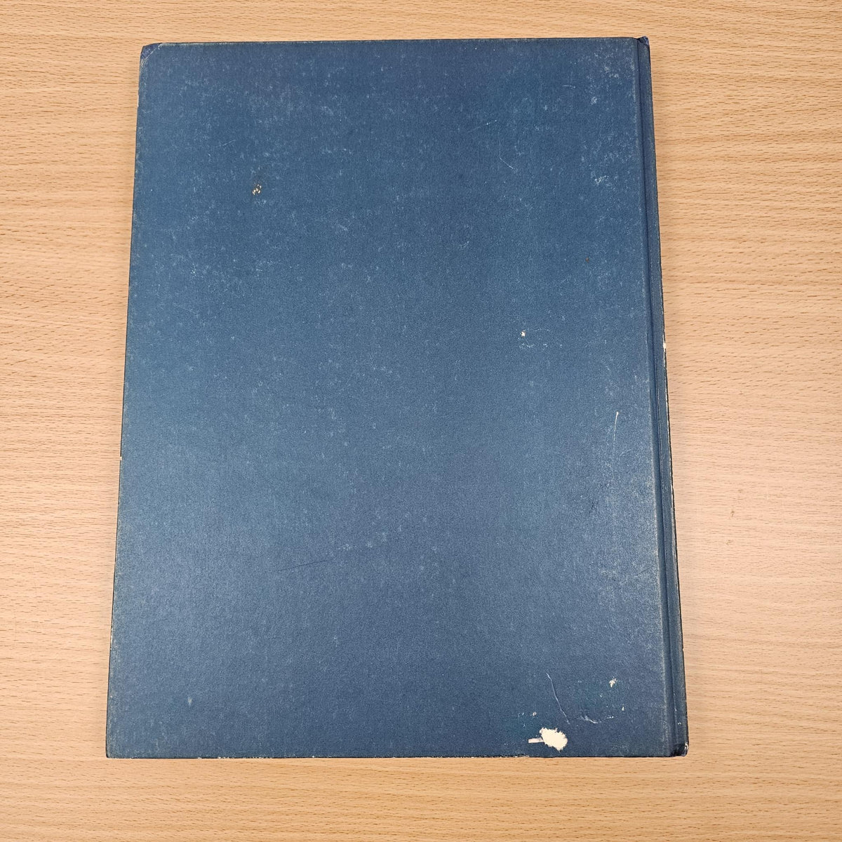 Blue automobile year reference book back cover, plain with small scuffs and wear.