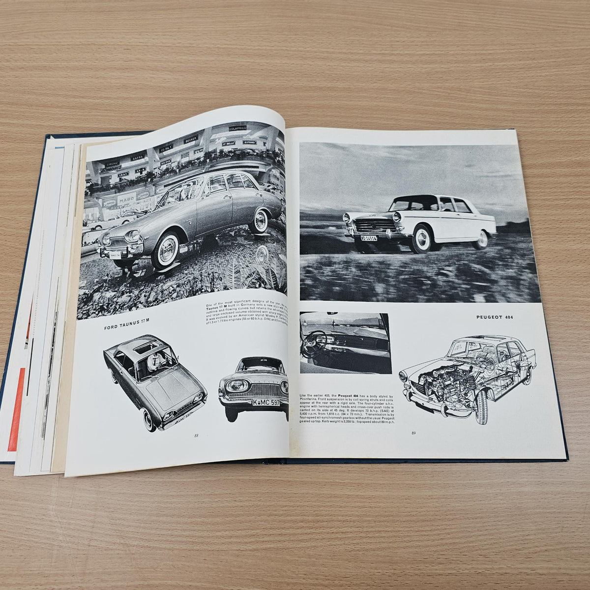 Open automobile year reference book with black-and-white vehicle photos and diagram captions.