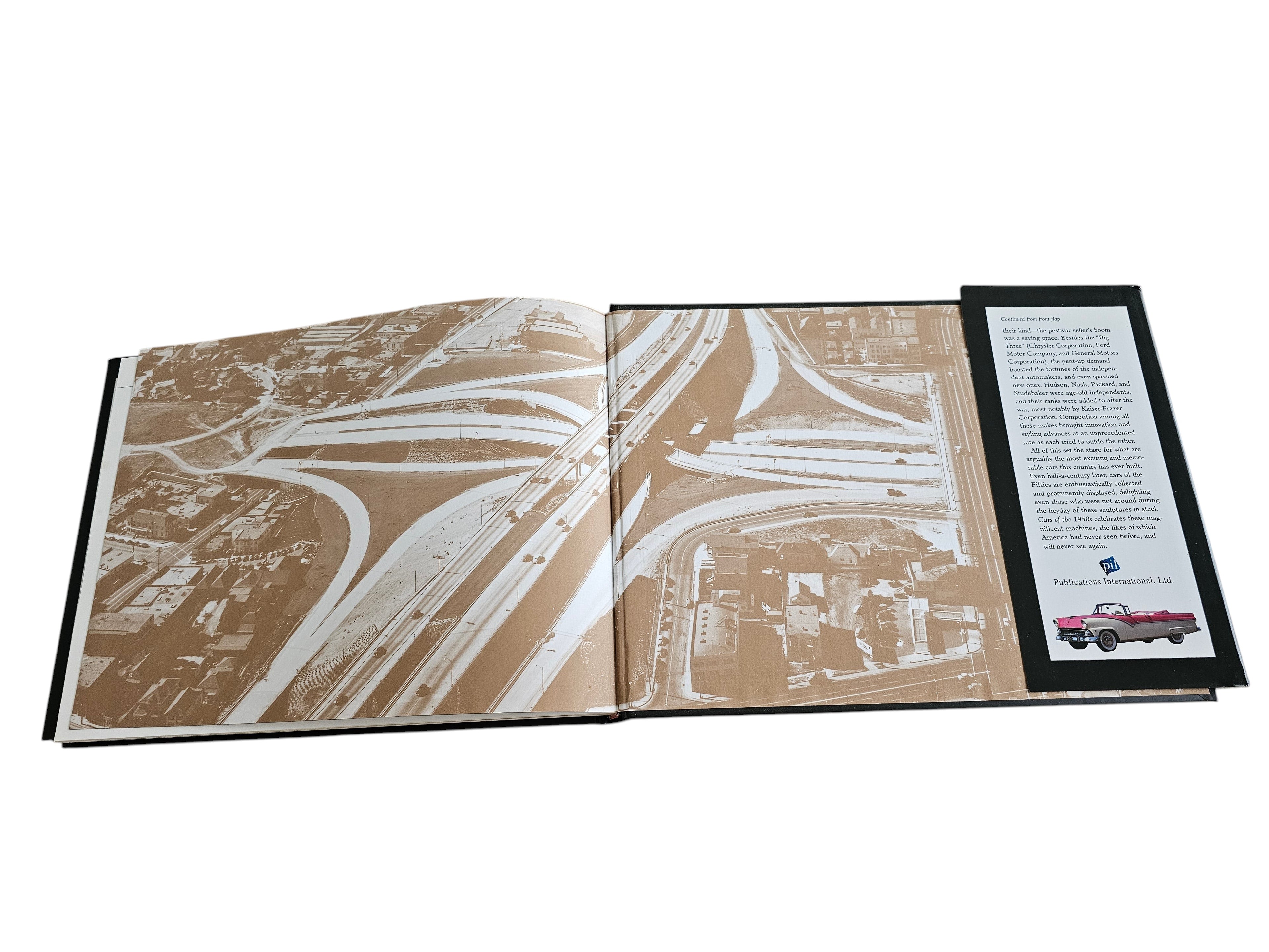Automoto Bookshop Cars of the 1950's hardcover book open to a page showing a vintage aerial view of a highway