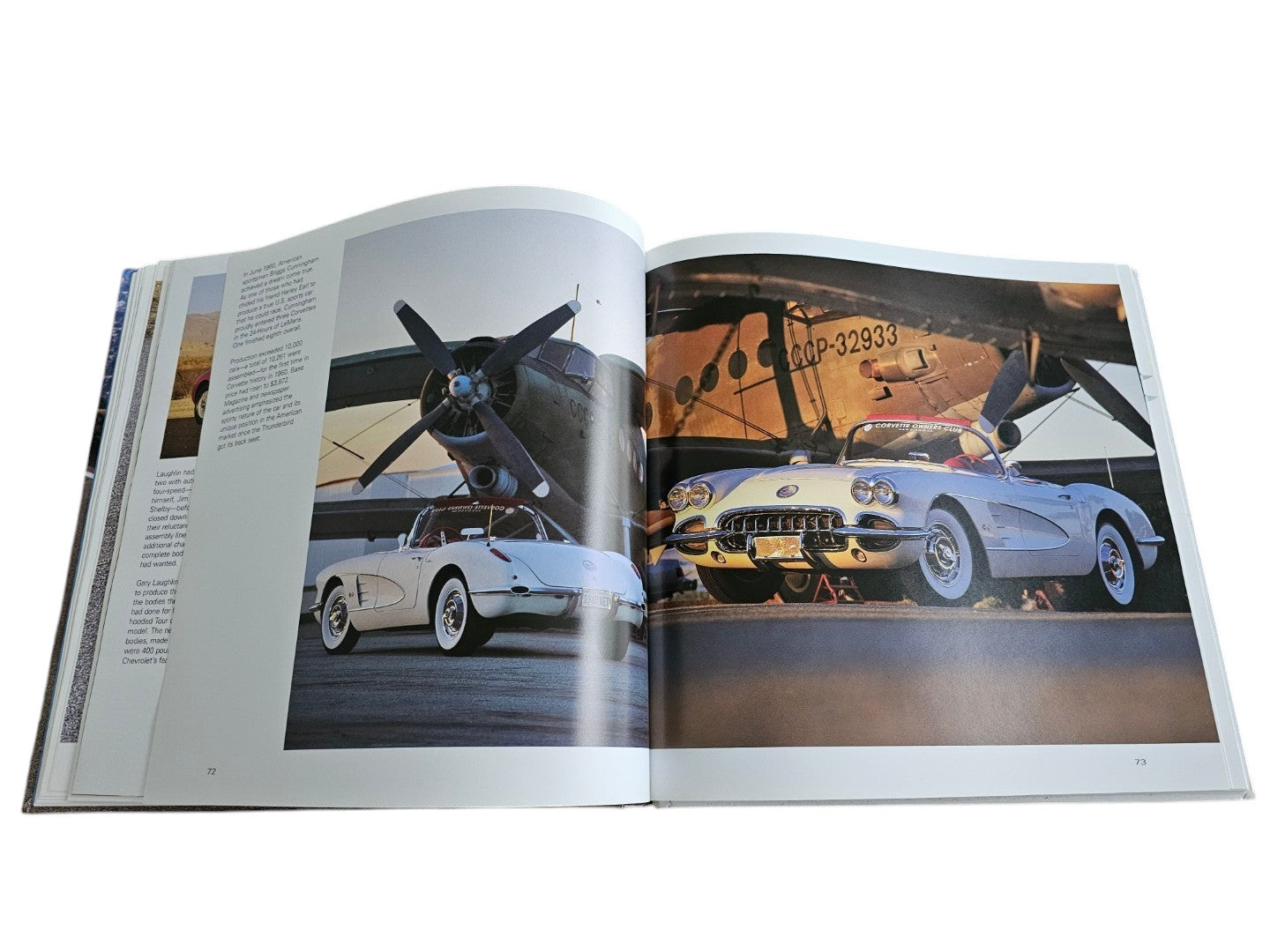 Automoto Bookshop hardcover book open to a page featuring vintage white Corvette sports cars parked by an airplane.