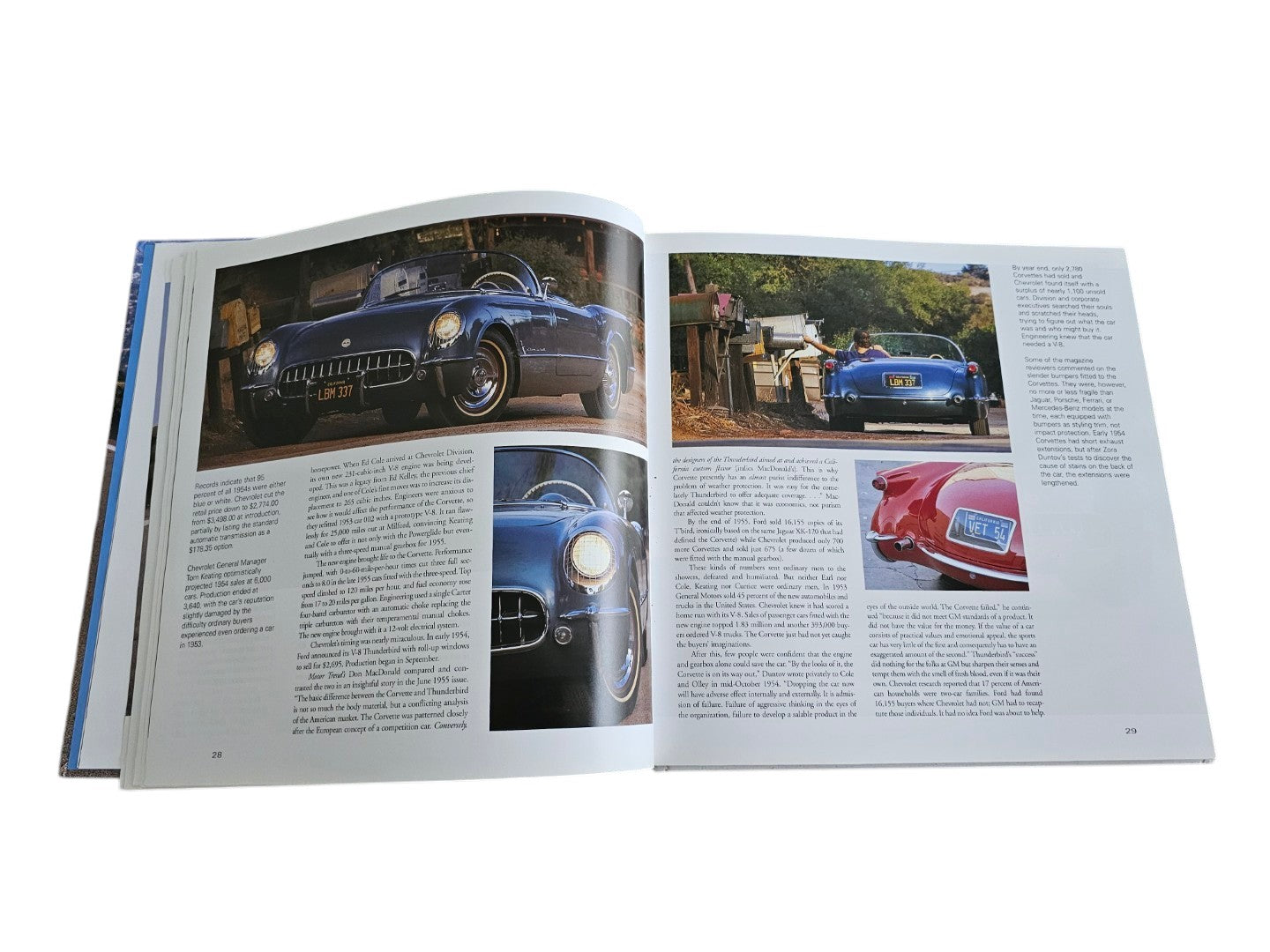 Automoto Bookshop hardcover book open to pages featuring vintage blue Corvette sports cars and historical text.