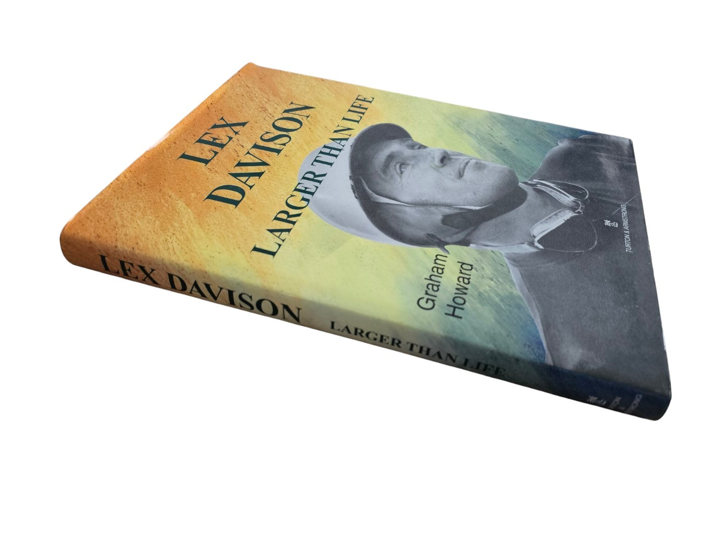 Automoto Bookshop rare multi-signed biography Lex Davison Larger Than Life by Graham Howard on a wooden surface.