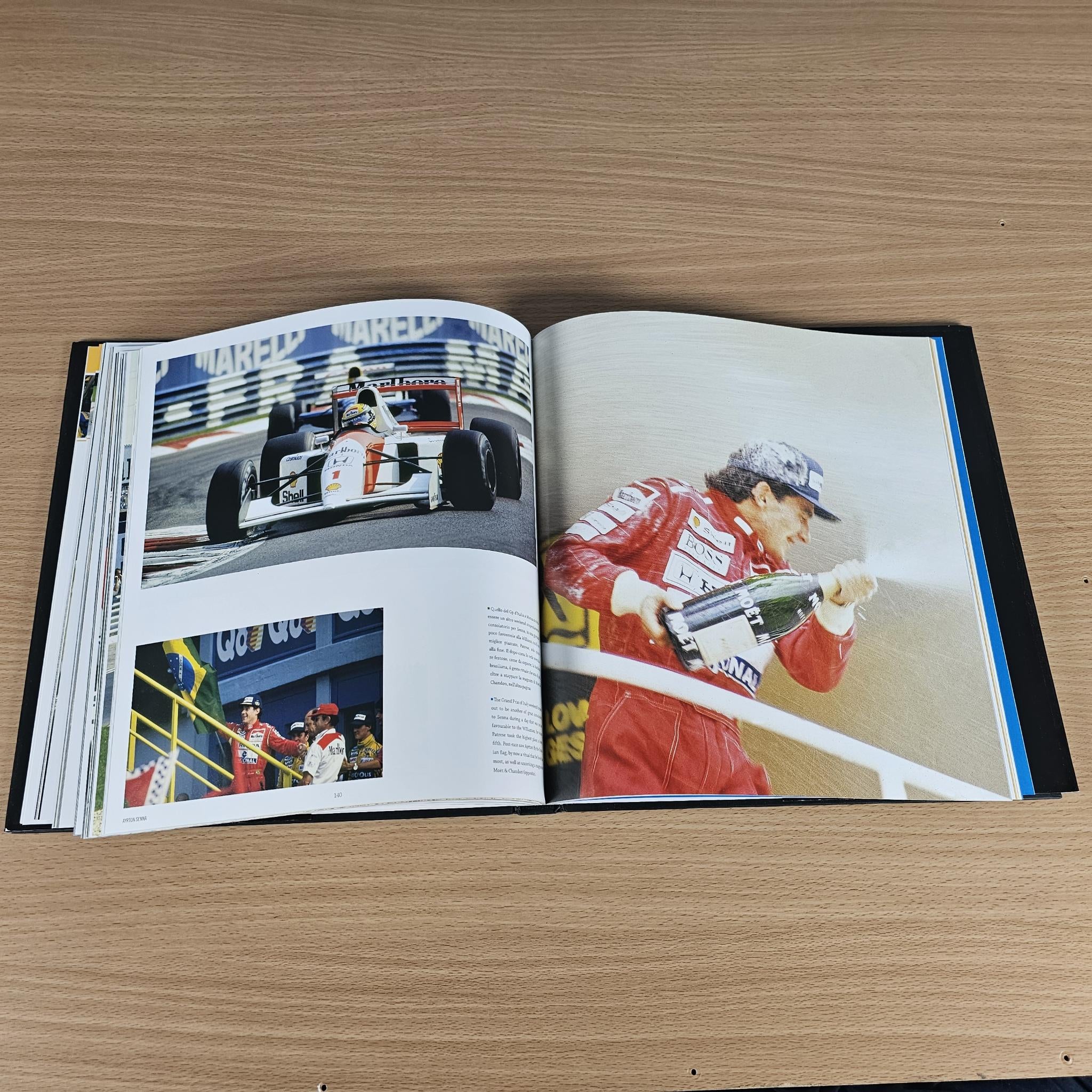Open hardcover book spread with racing photos and portrait of Senna in a red suit.