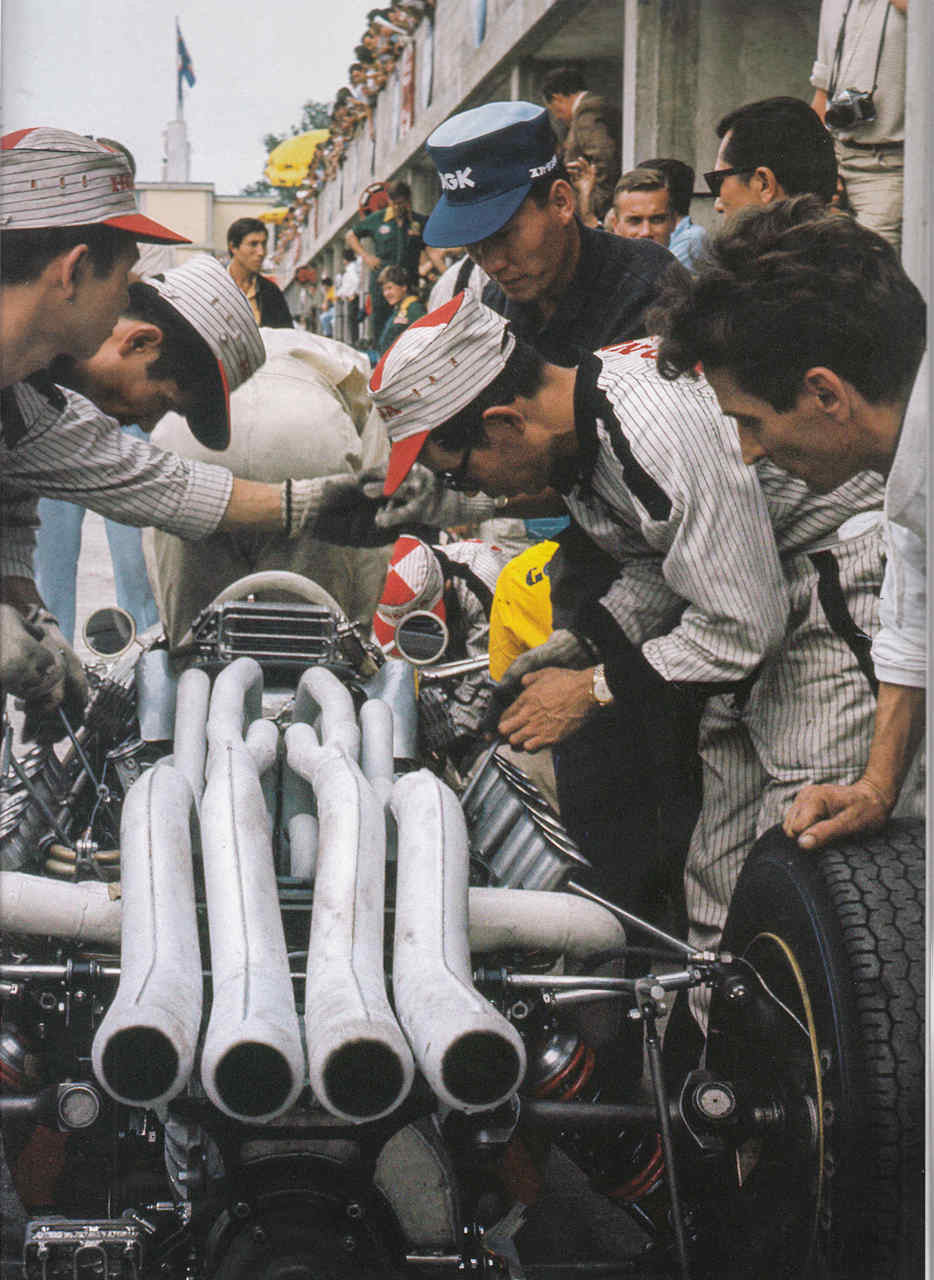 Paperback book cover showing crowd around a race car engine and tires