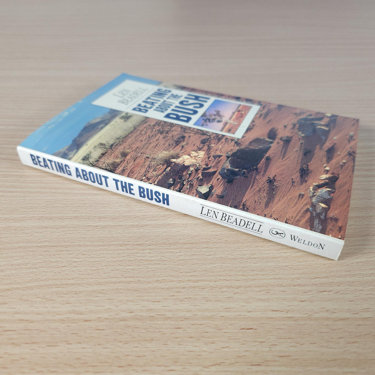 Hardcover book lying on a wood surface, showing title, author, and publisher on spine