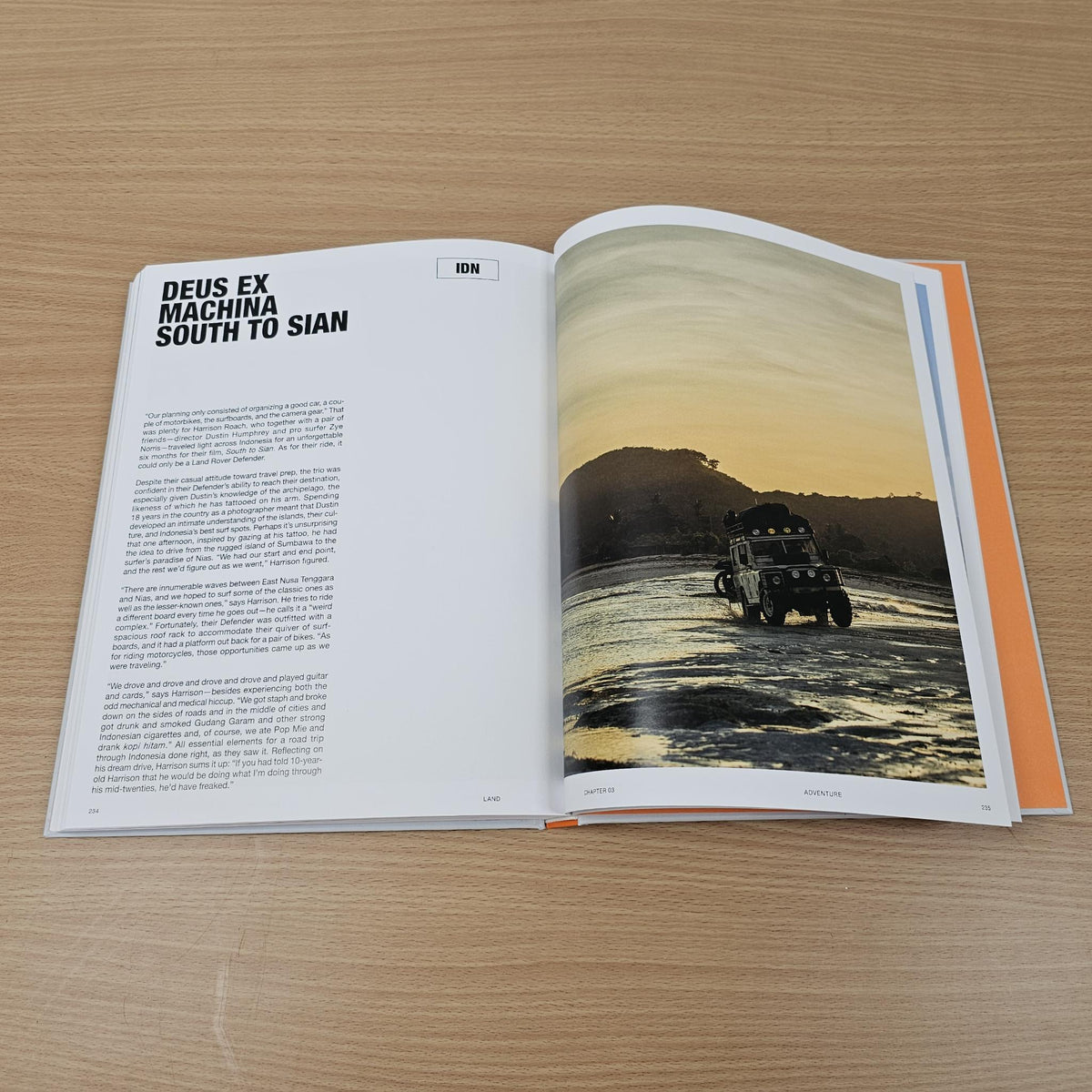 Open photo book spread with off-road vehicle driving along coastal road on right page