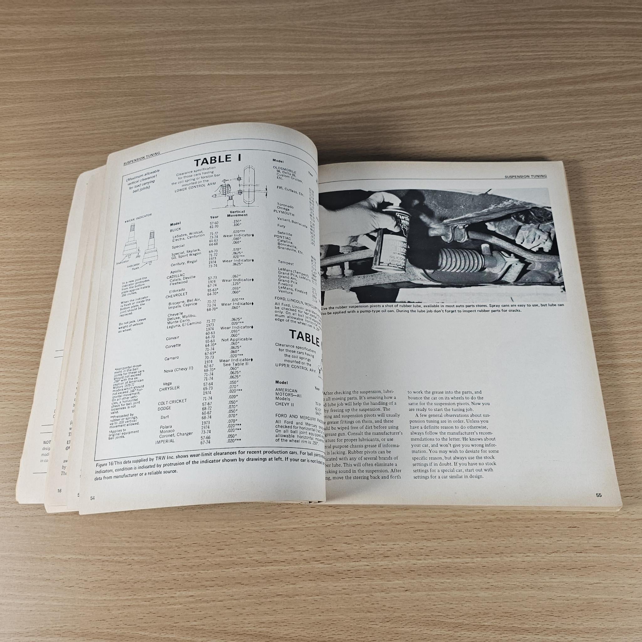 Open car handling guidebook with technical table pages and grayscale workshop photos