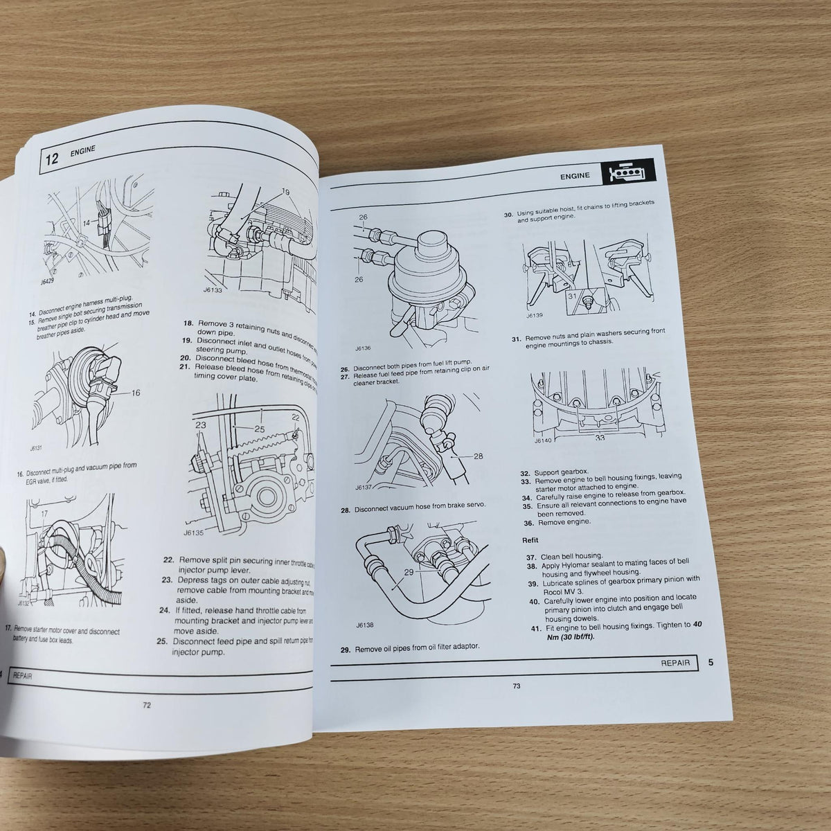 Workshop manual open to engine repair diagrams with labeled parts and instructions