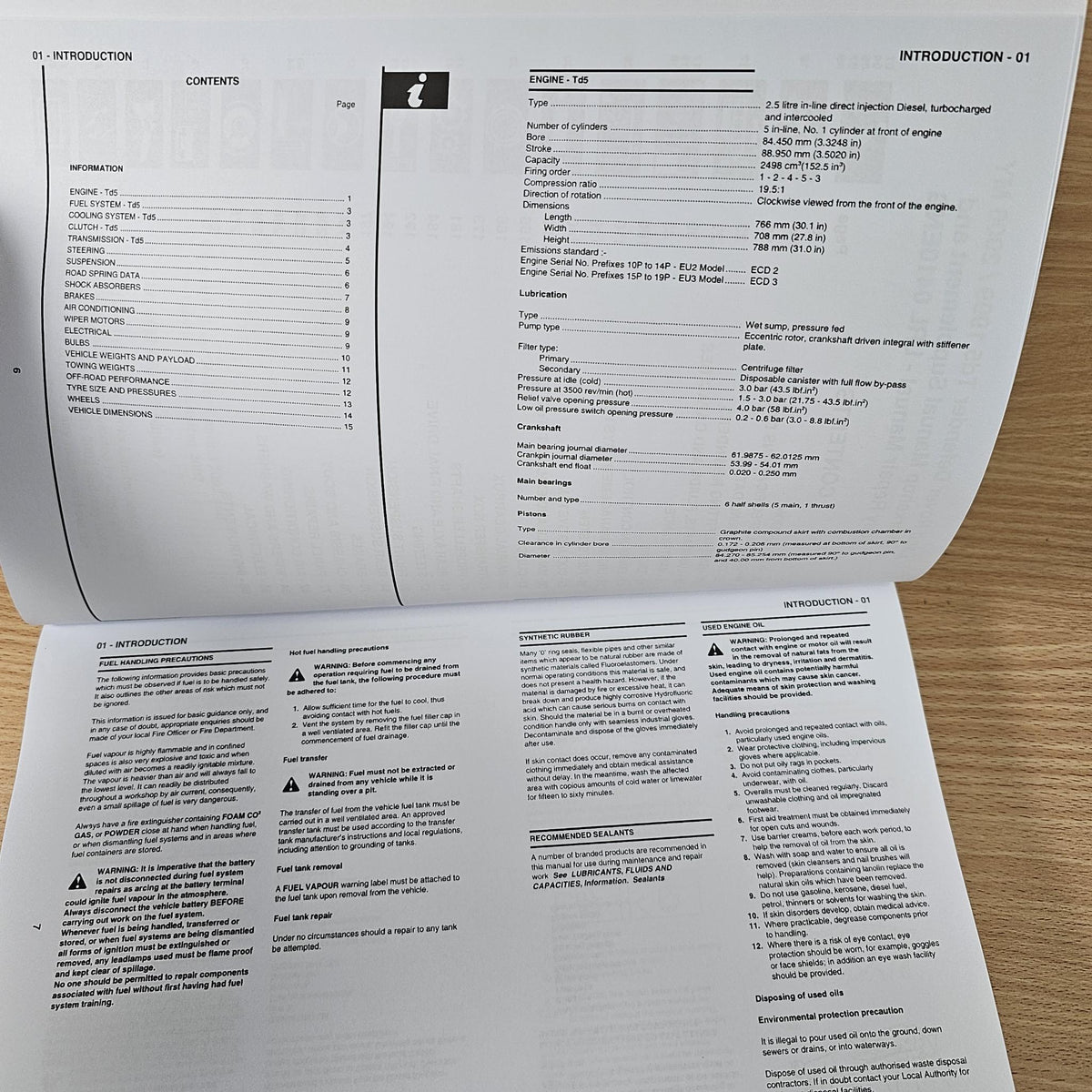 Workshop manual open to introduction pages with paragraphs and warnings