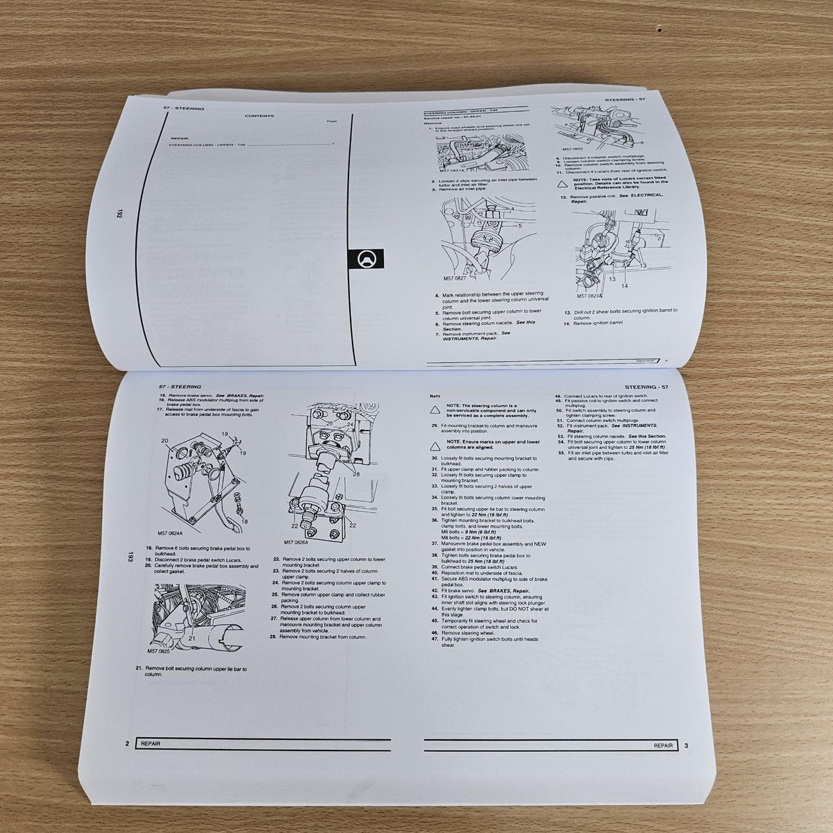 Workshop manual open to technical pages with diagrams and step-by-step instructions