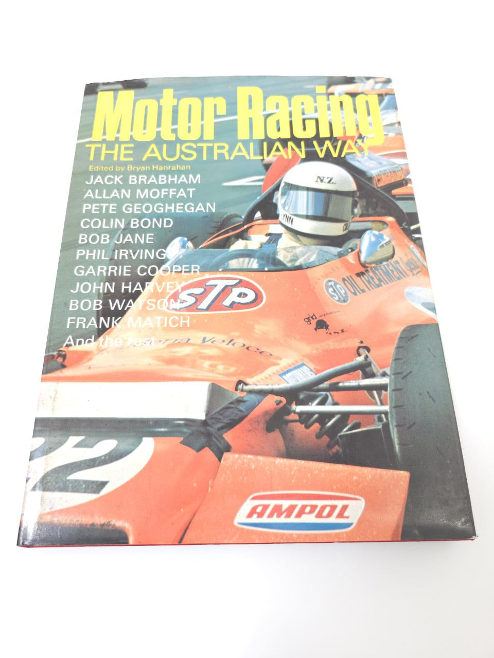 Hardcover racing book, front cover angled view with orange race car artwork and title