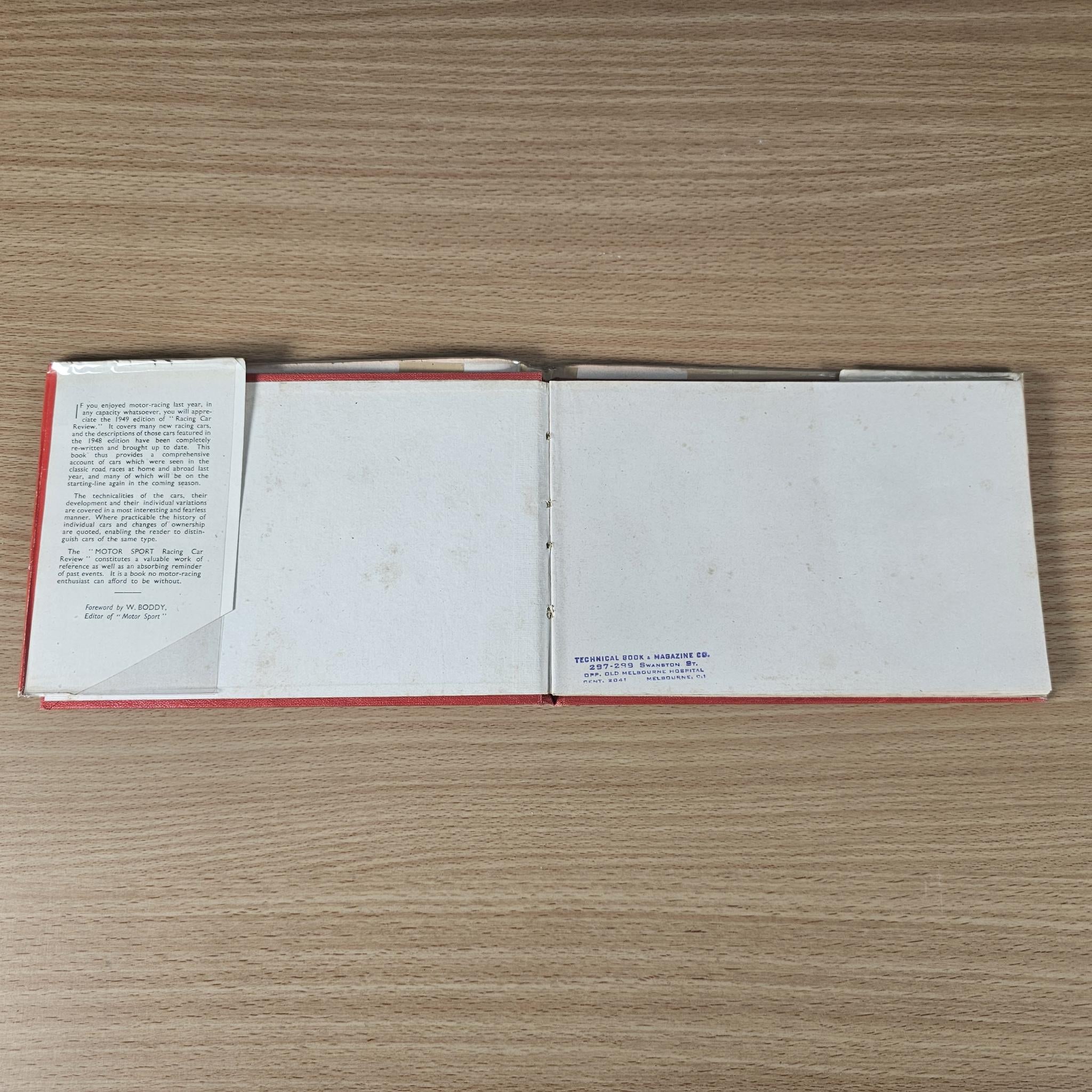 Open vintage book with white pages and left text panel; red binding edge.