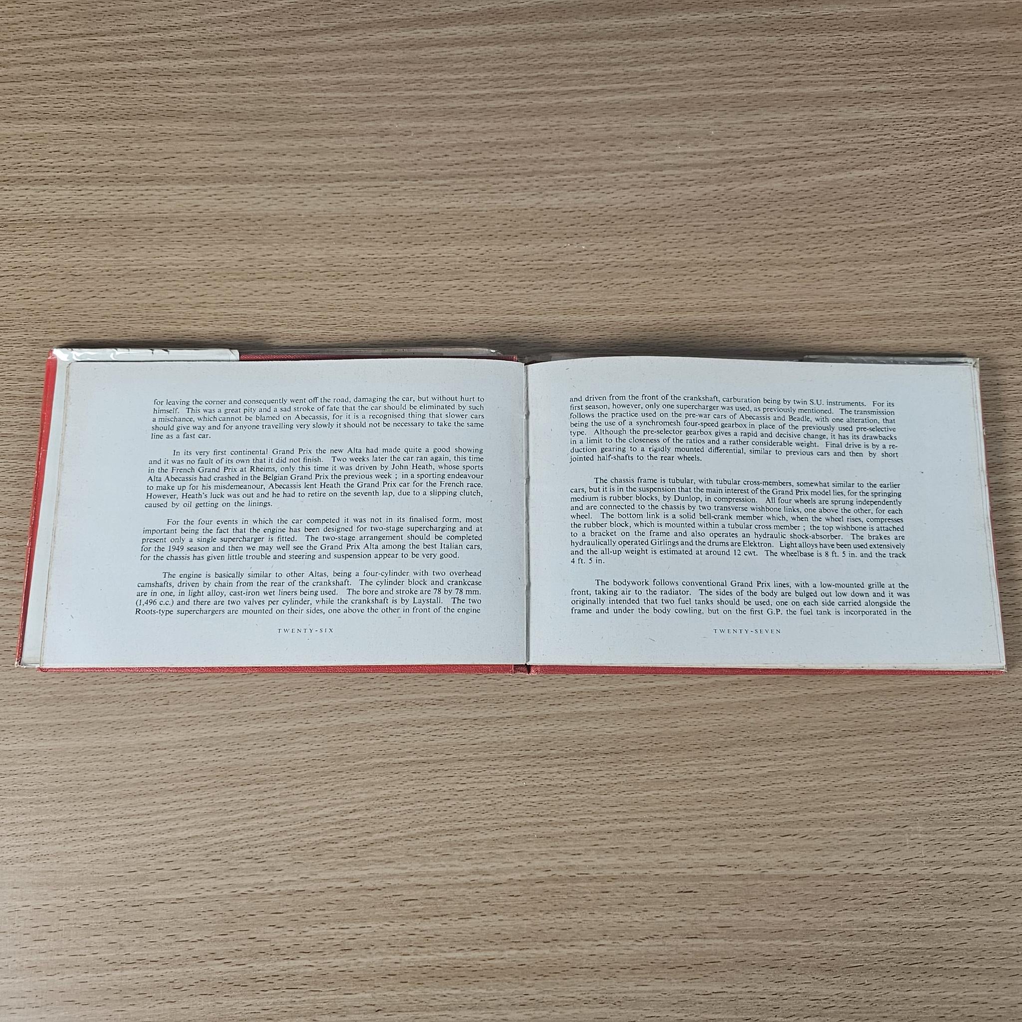 Open vintage book spread with two pages of text; red spine trim visible.