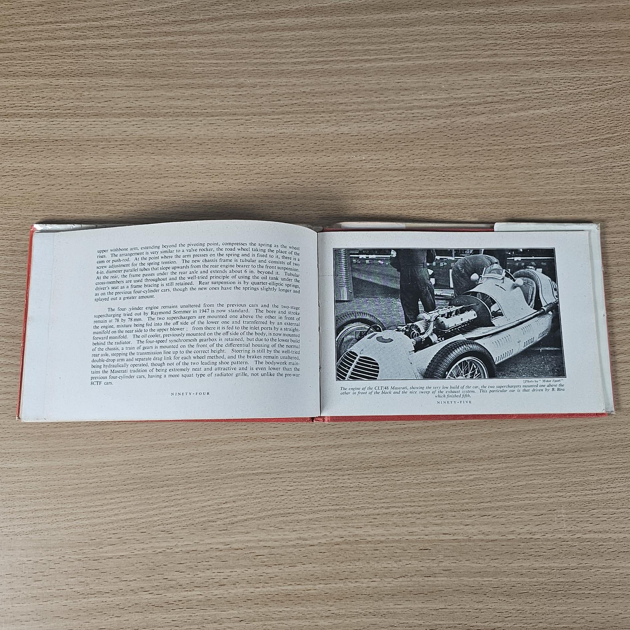 Open vintage book spread with text on left and black-and-white race car image on right.