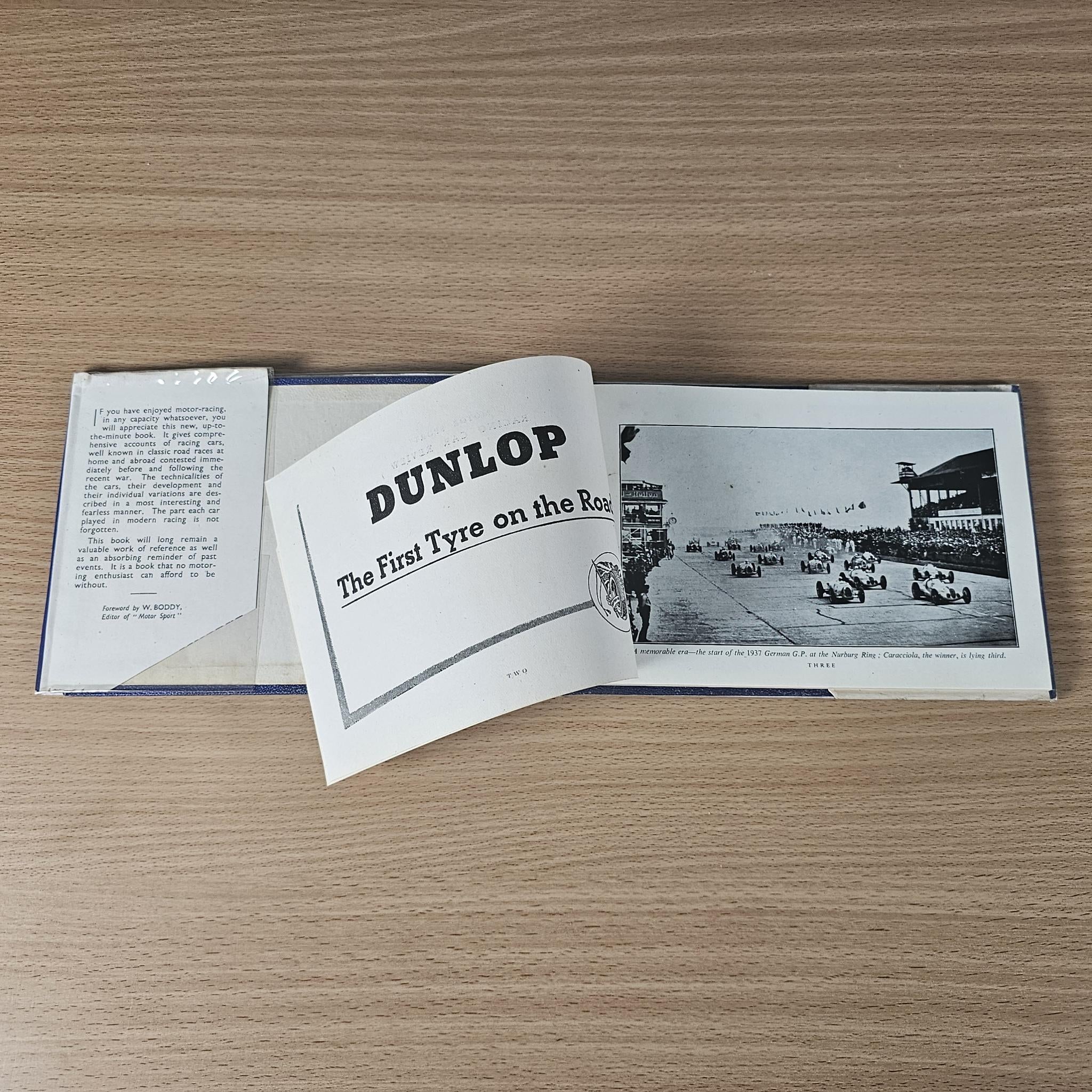 Racing car review book open with “DUNLOP” title card and race track photo