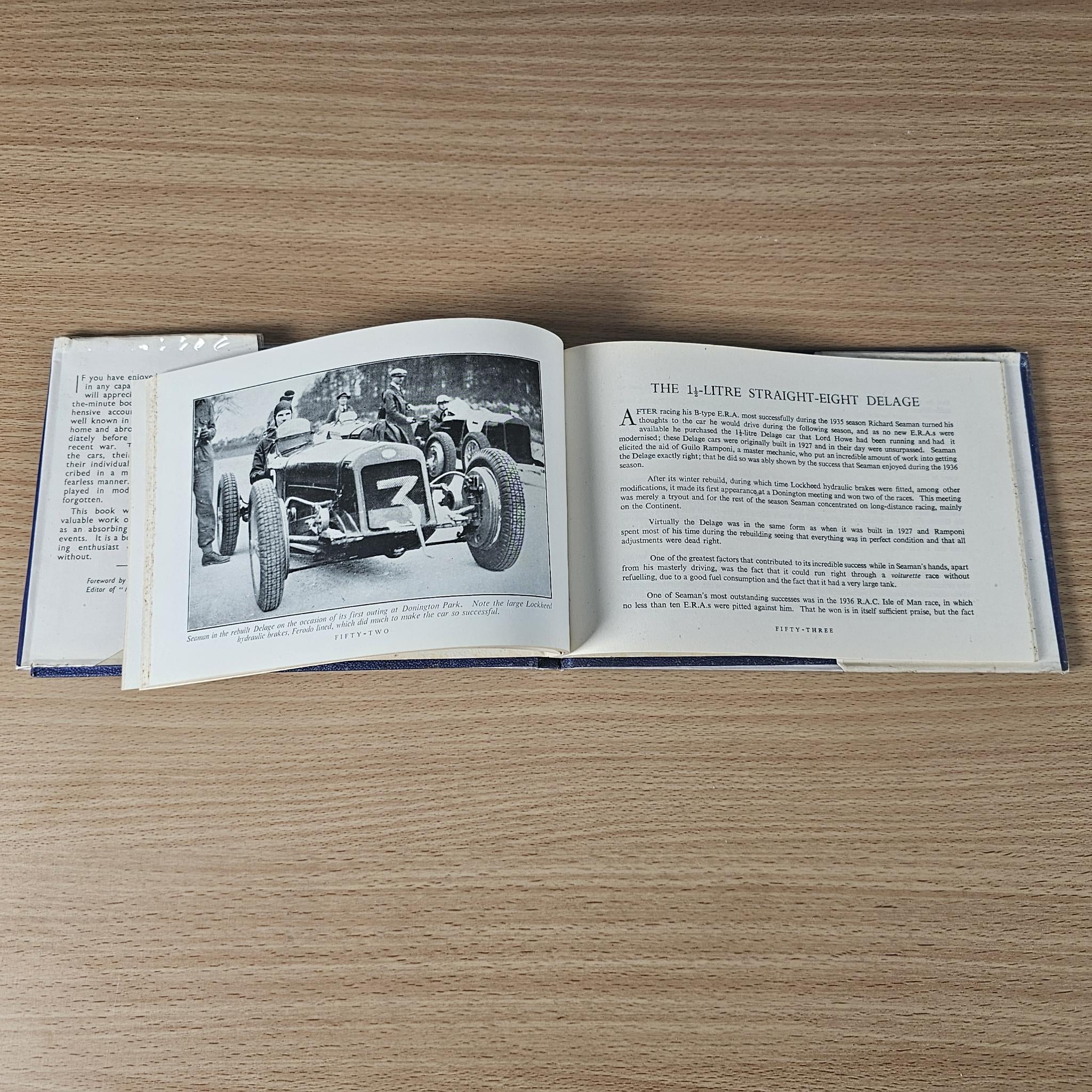 Racing car review book open to a page with vintage car photo and technical description