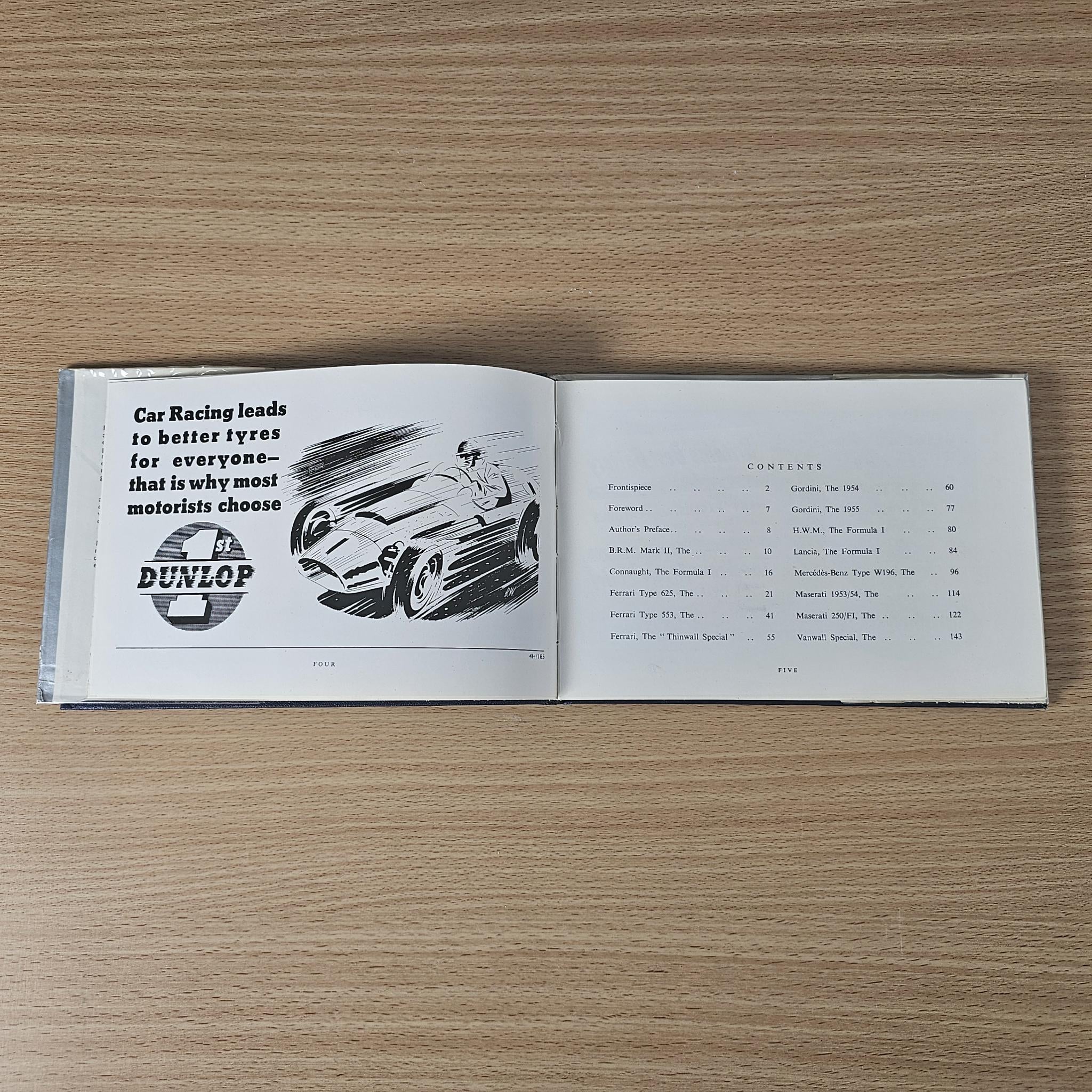 Open vintage racing car review book with Dunlop advertisement and racing diagram