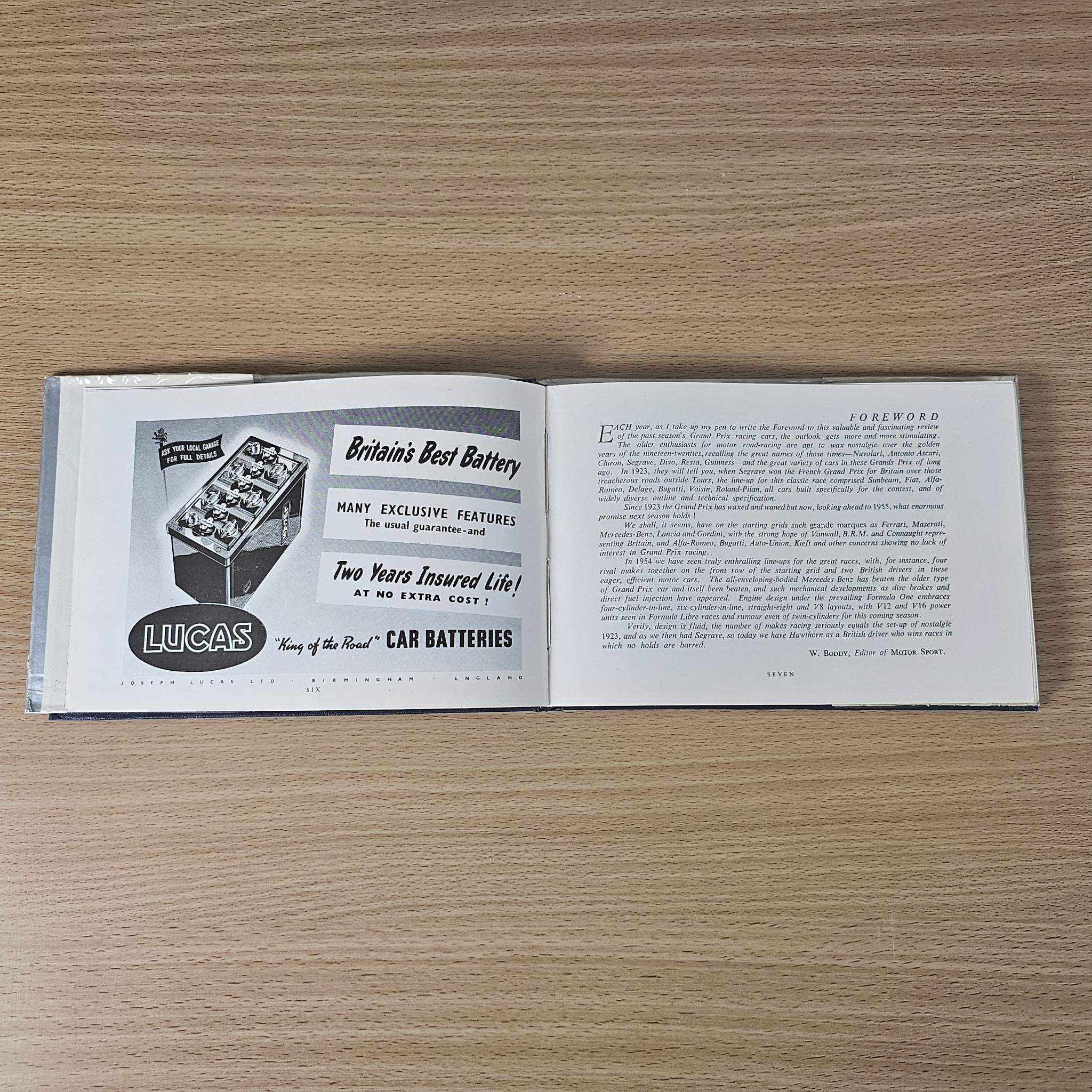 Open vintage racing car review book with Lucas car batteries advertisement