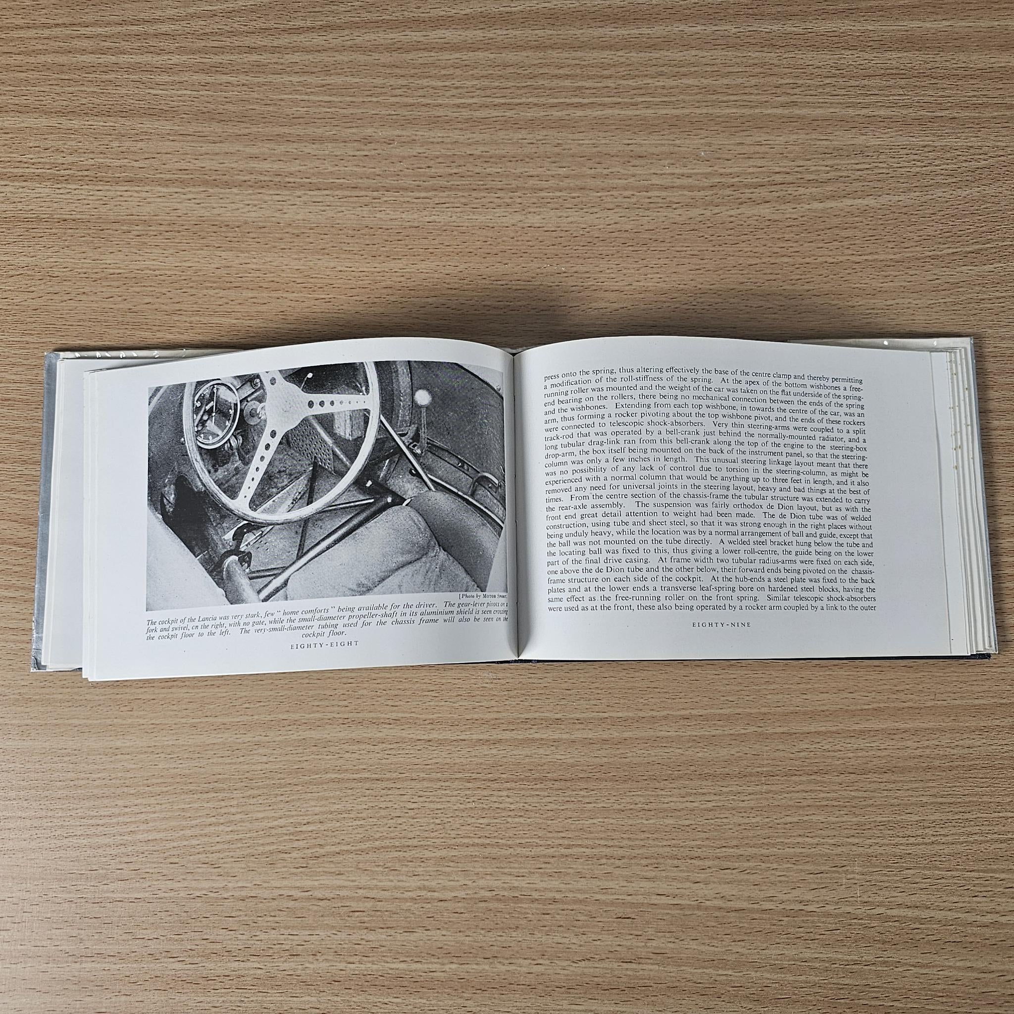 Open vintage racing car review book with steering close-up photo and paragraphs