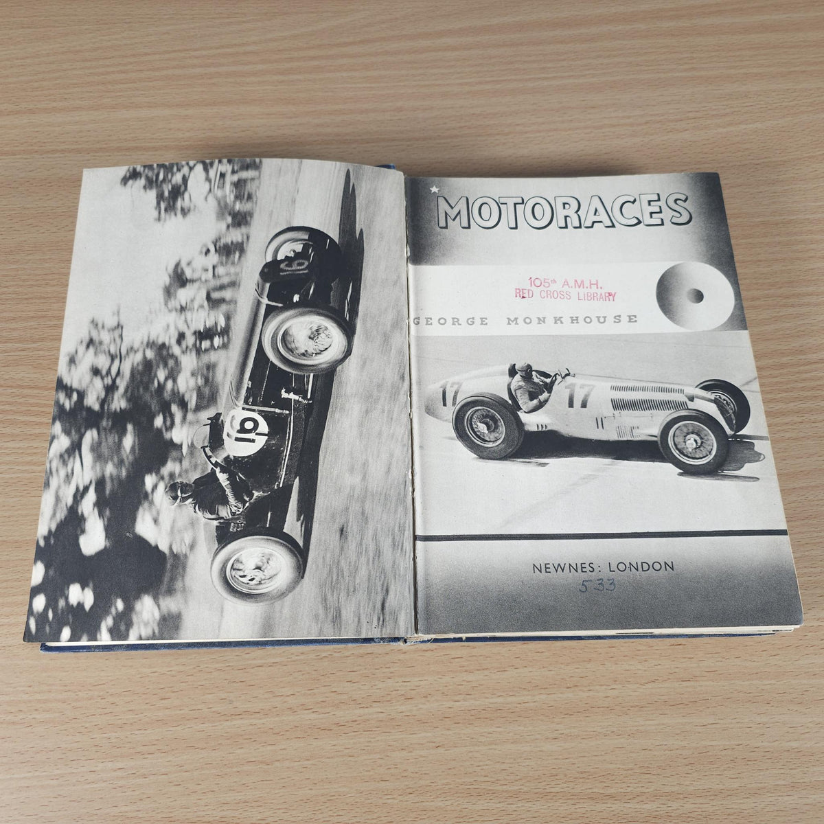Vintage racing book open, showing blue title page and black-and-white race car photos