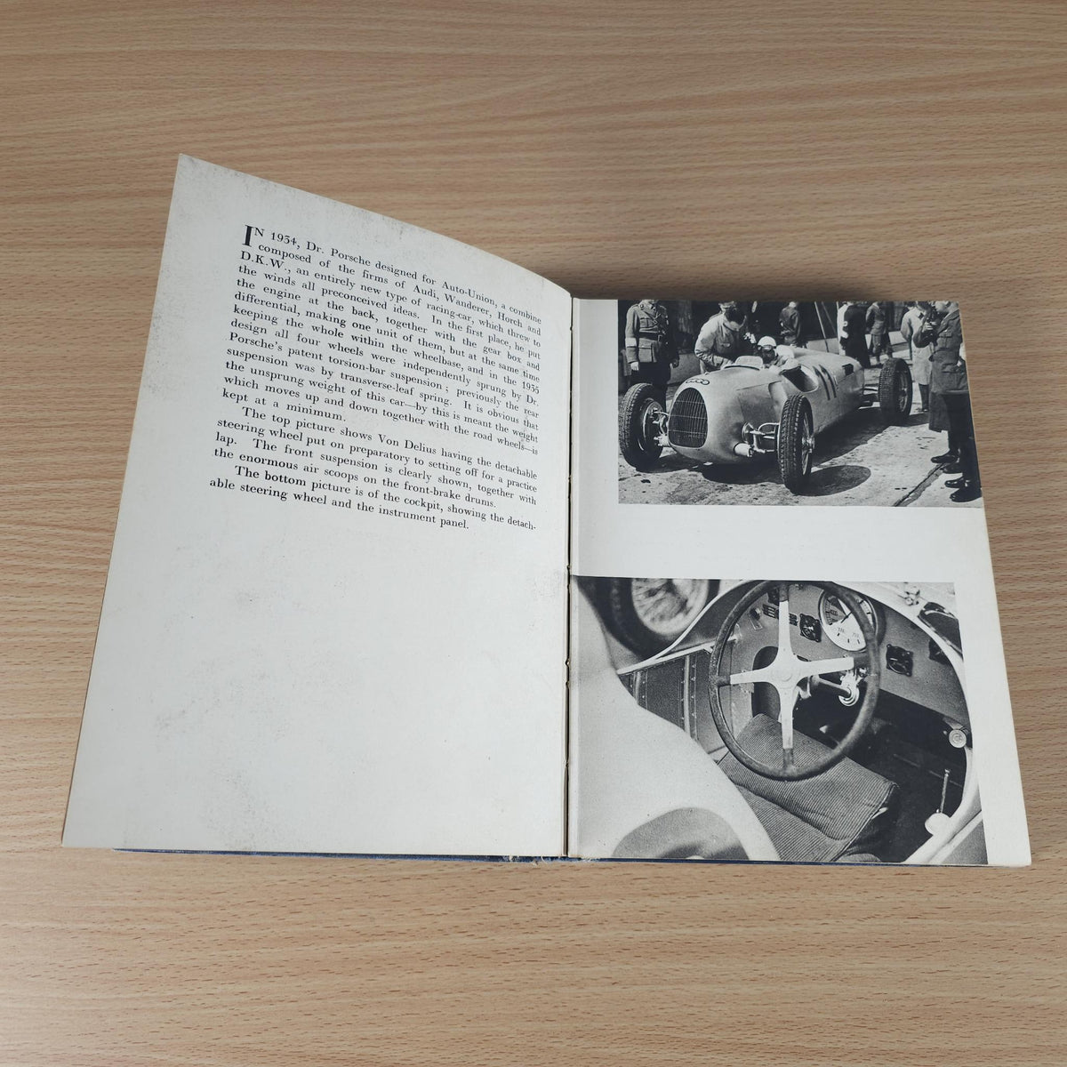 Vintage racing book open, with printed paragraphs and black-and-white car photographs