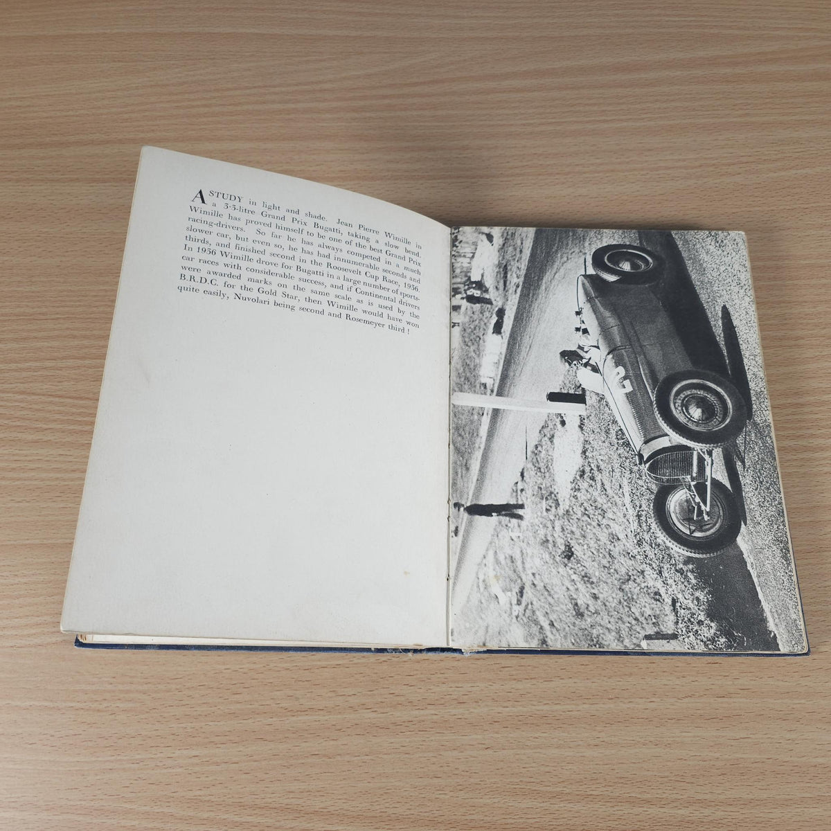Vintage racing book open, with printed text and a large black-and-white race car image