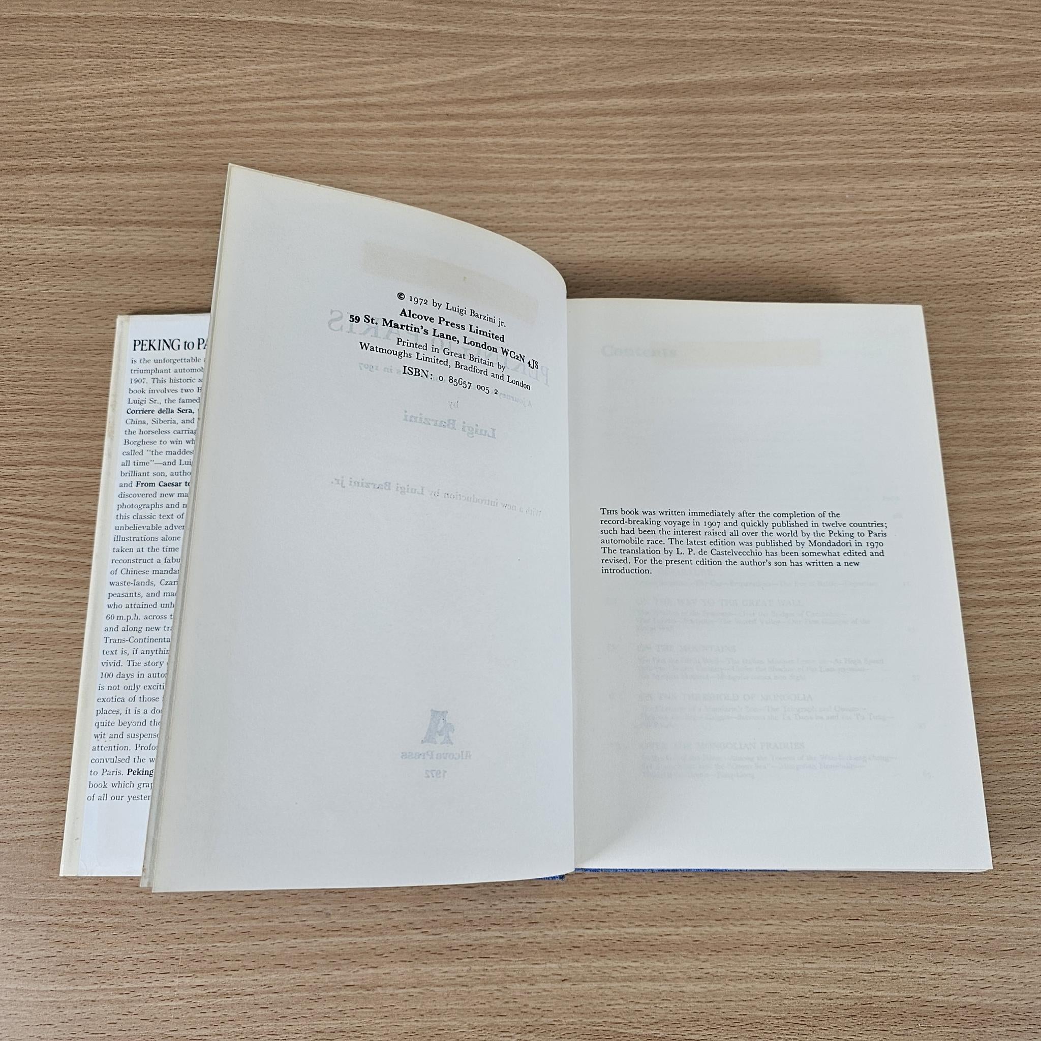 Hardcover book open to interior pages with paragraphs and small decorative emblem