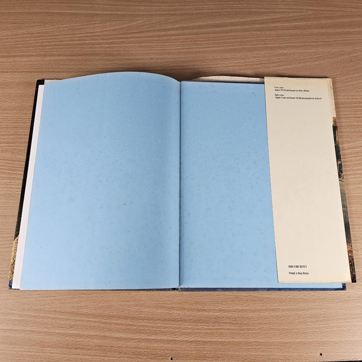 Open Jaguar sports book with blank blue pages and a printed information card