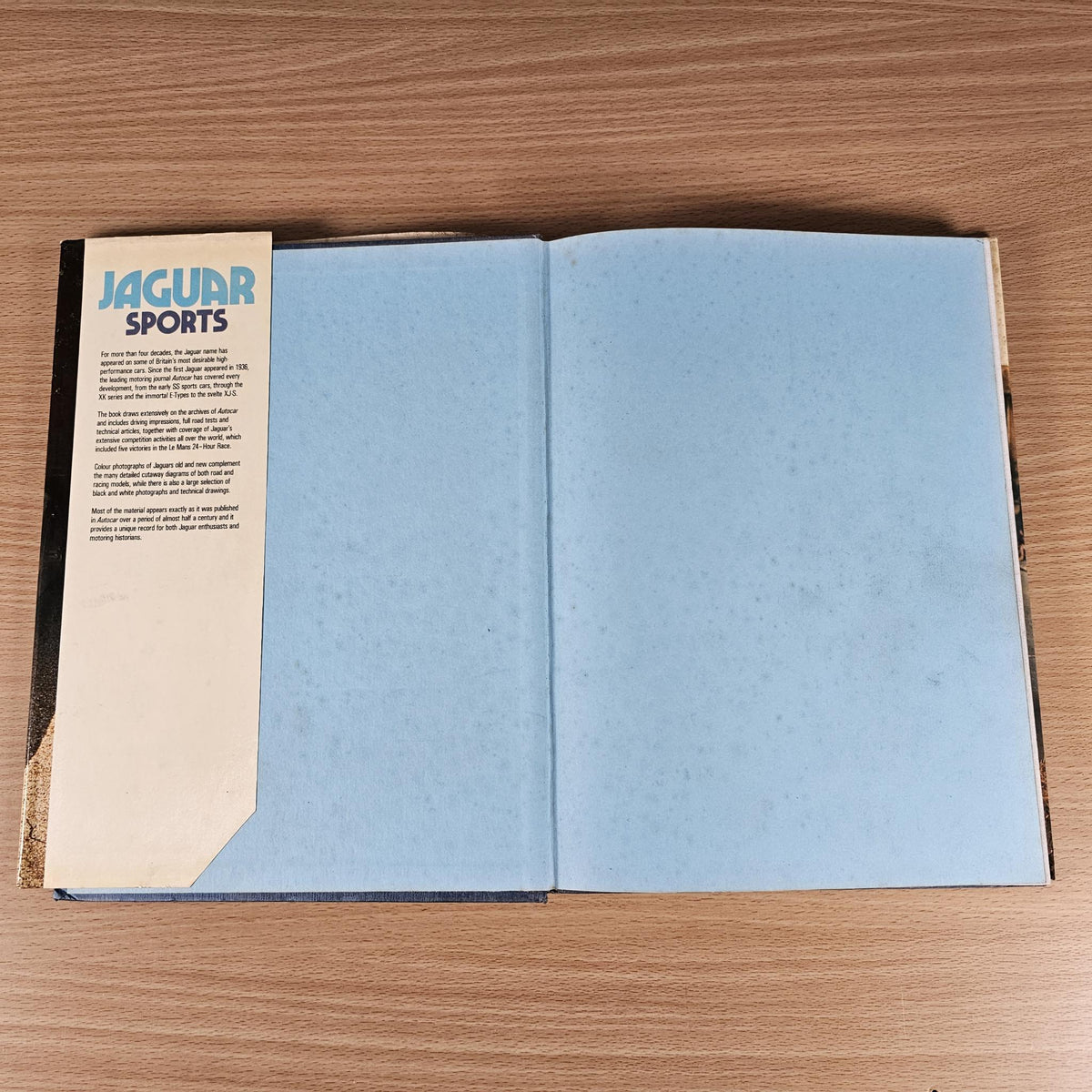 Open vintage car book with light blue blank pages and small Jaguar Sports header