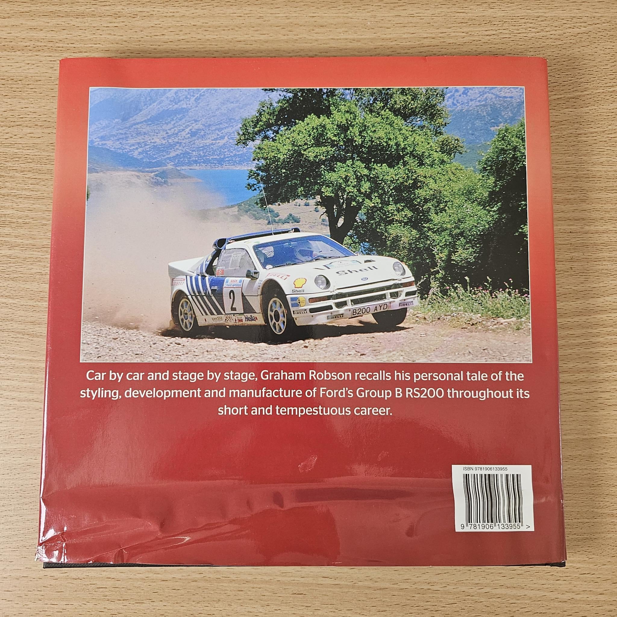 Racing book with red back cover and rally car action photo on landscape background.