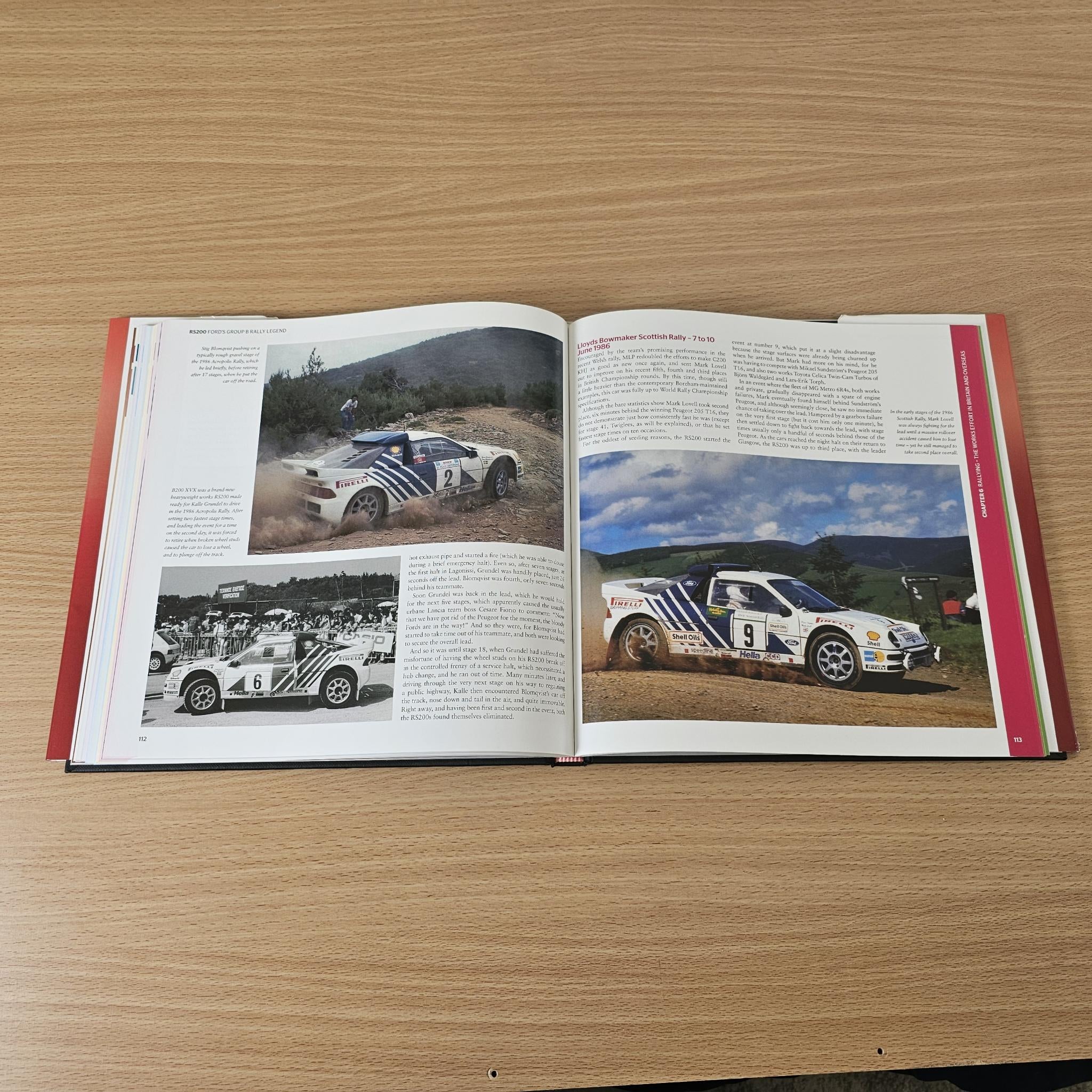 Open rally book with rally car photos across two pages and dense paragraph text.