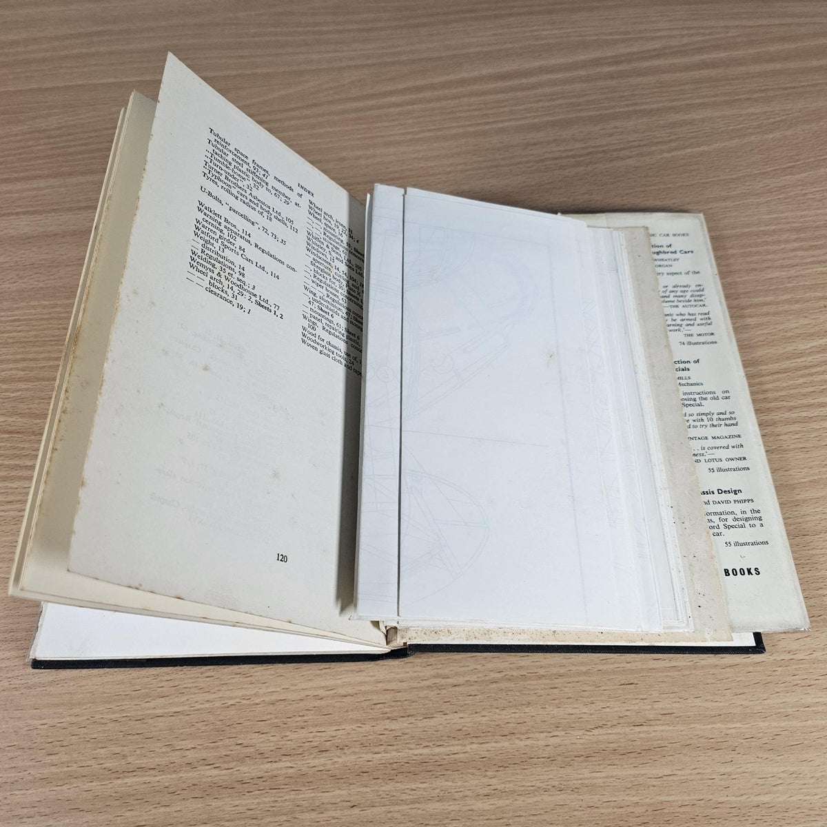 Hardcover book opened to illustrated blueprint pages and dense text