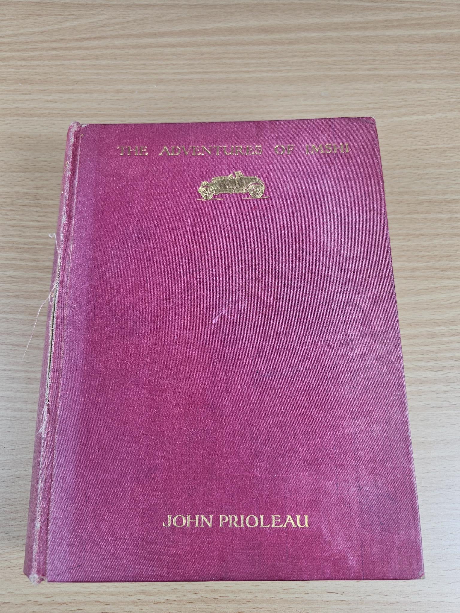 Maroon vintage hardcover book with gold emblem and author name on cover
