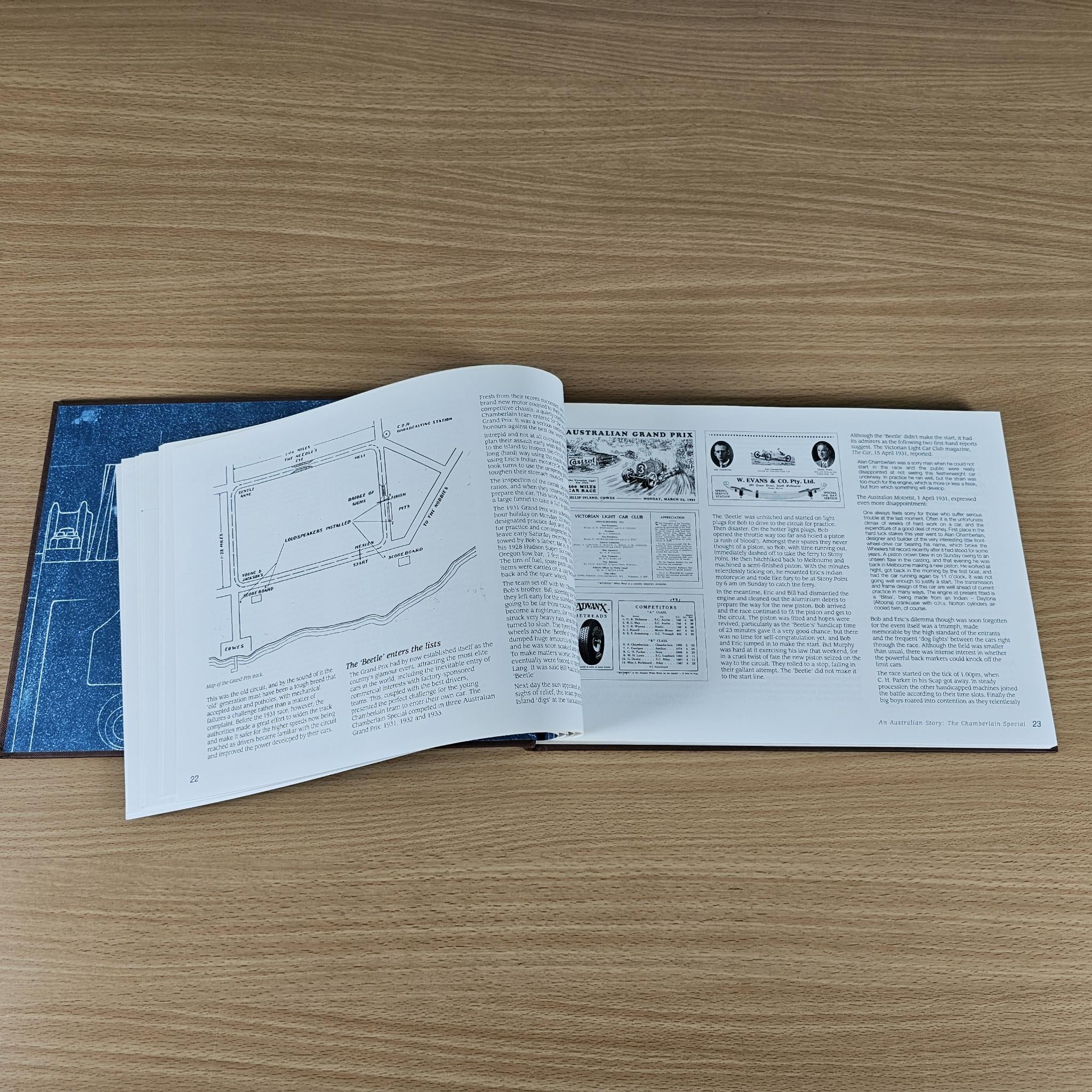 Open book with white pages, blue technical diagrams, and black-and-white photo spreads