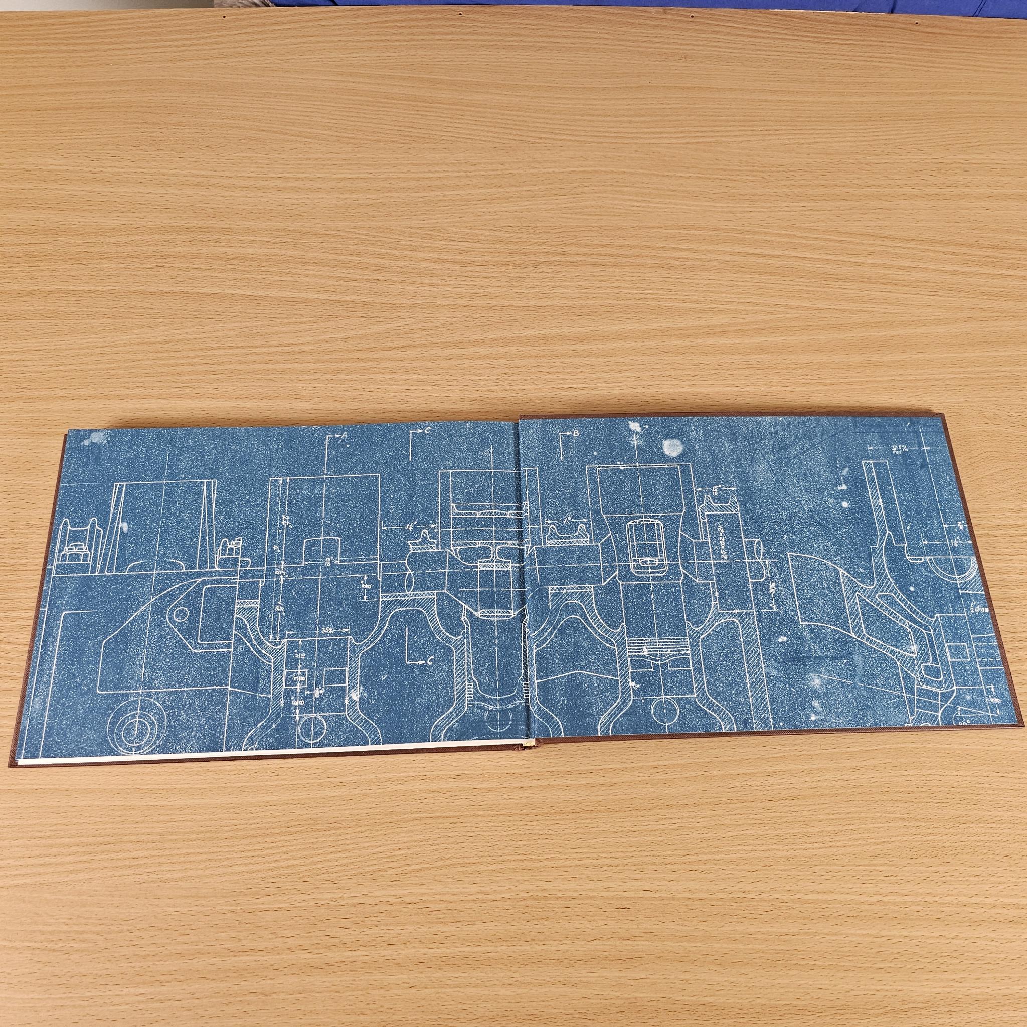 Opened book cover spread with blue blueprint-style line art and circuit diagrams