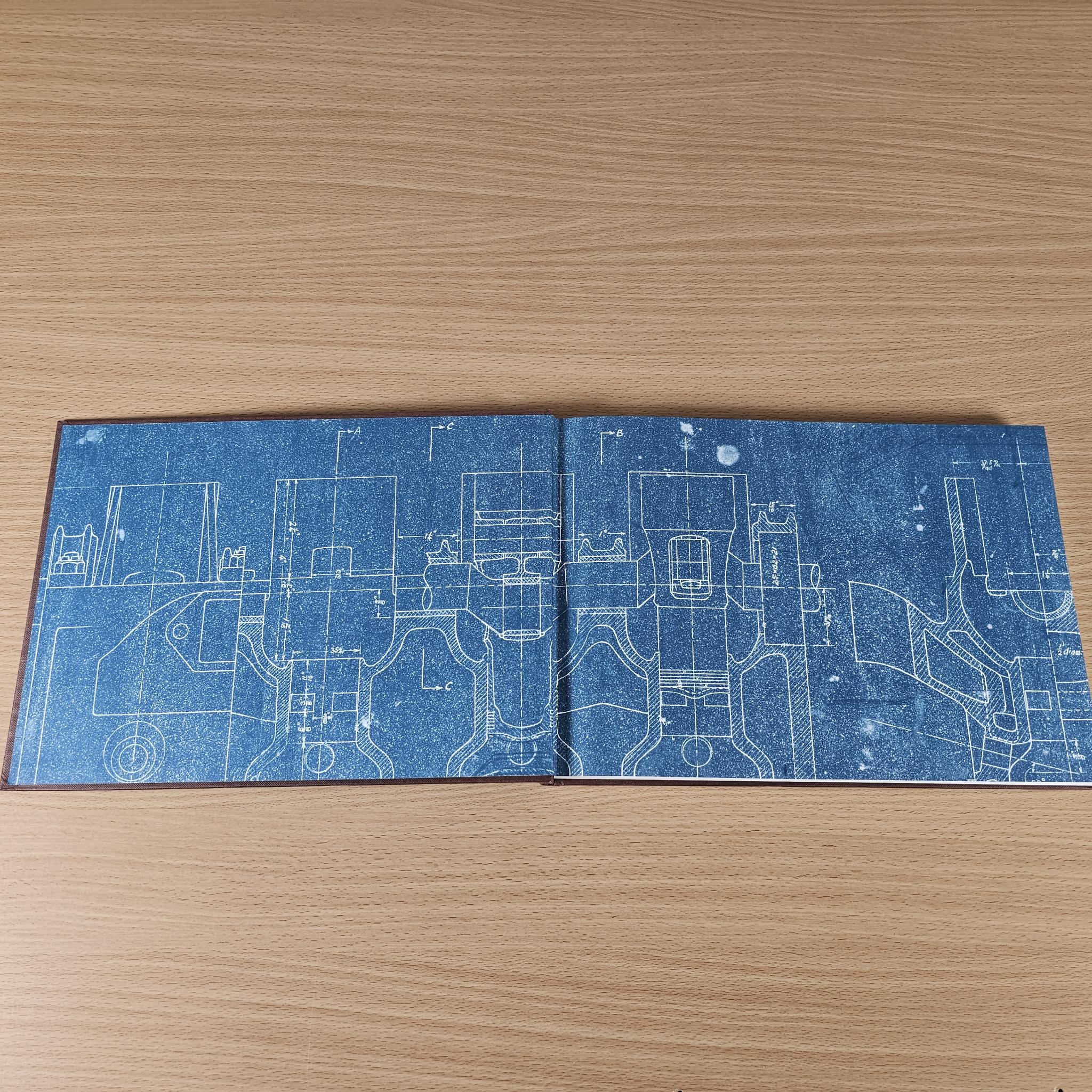 Blue book cover with white blueprint-style vehicle diagrams pattern