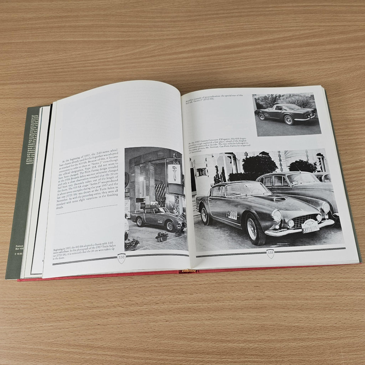 Open vintage sports car photo book with black-and-white car image spread.