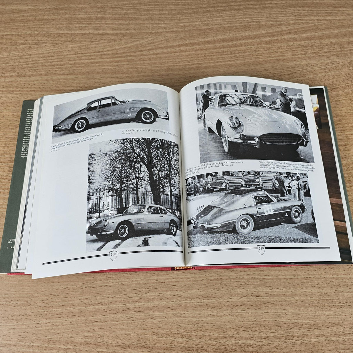 Open vintage sports car photo book with black-and-white car images spread.