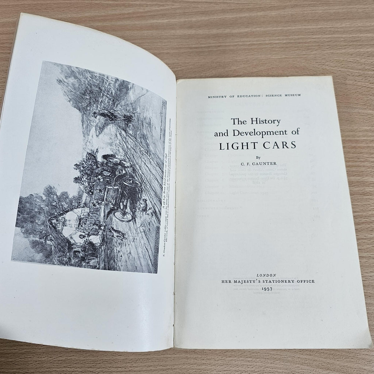 Open paperback book showing title and author text, with grayscale vehicle illustration